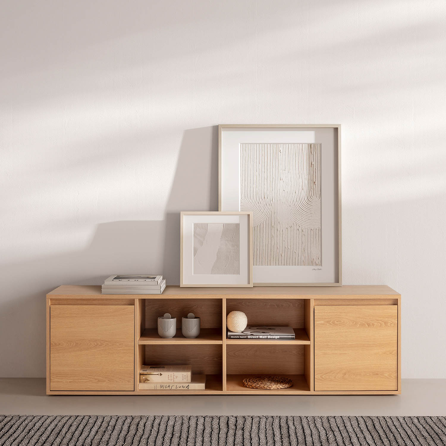 Un aparador de madera con dos cuadros, libros y objetos decorativos.