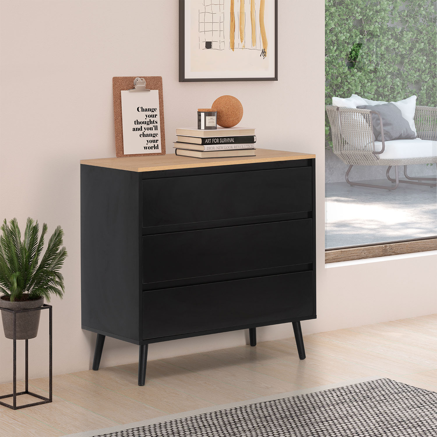 Cómoda negra con tapa de madera, planta, libros y arte enmarcado.