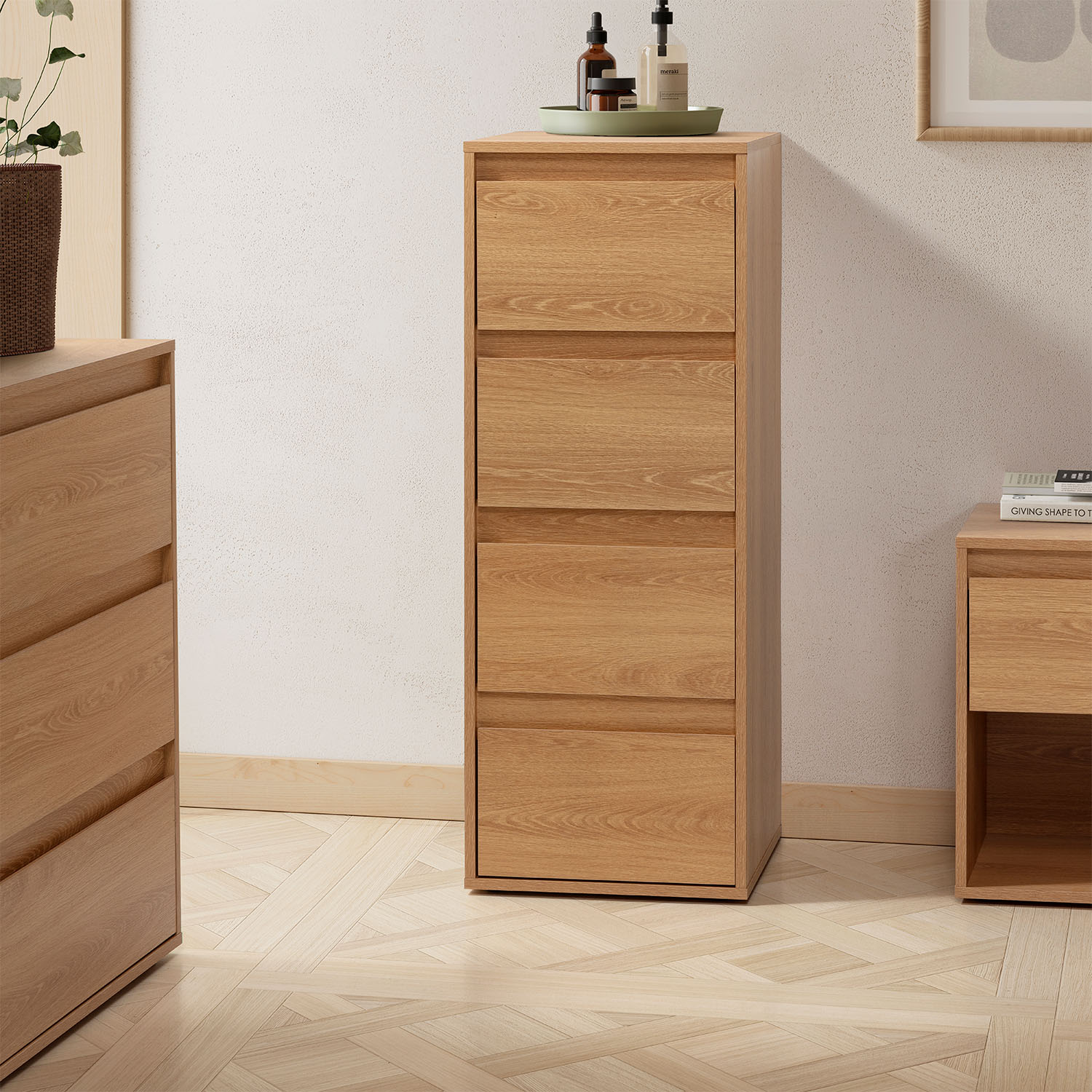 Una cómoda alta de madera clara con cinco cajones se alza sobre un suelo de madera.