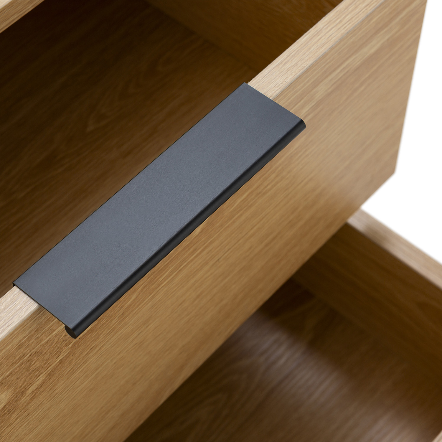 Primer plano de un cajón de madera con un tirador gris oscuro. El cajón está abierto.