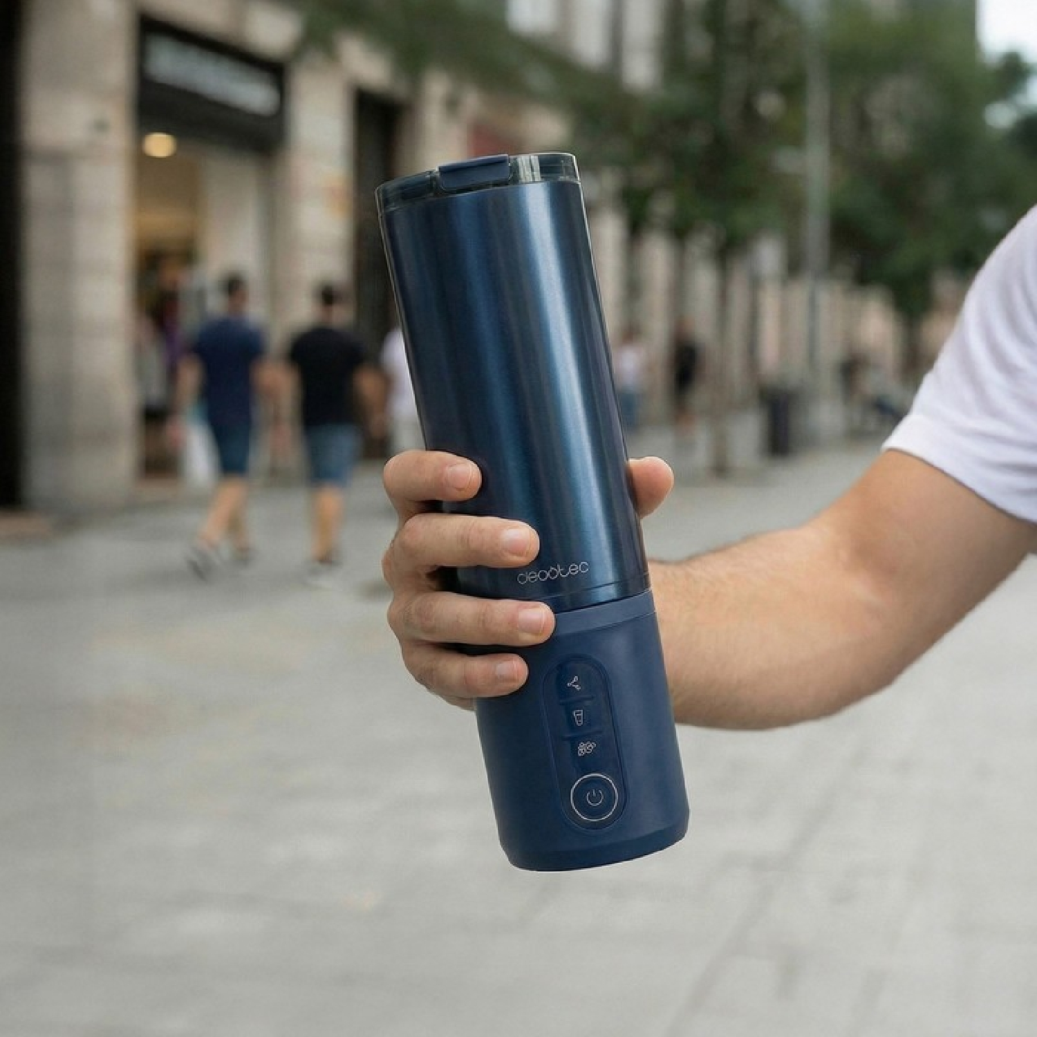 Una persona sostiene una taza batidora azul con controles al aire libre.