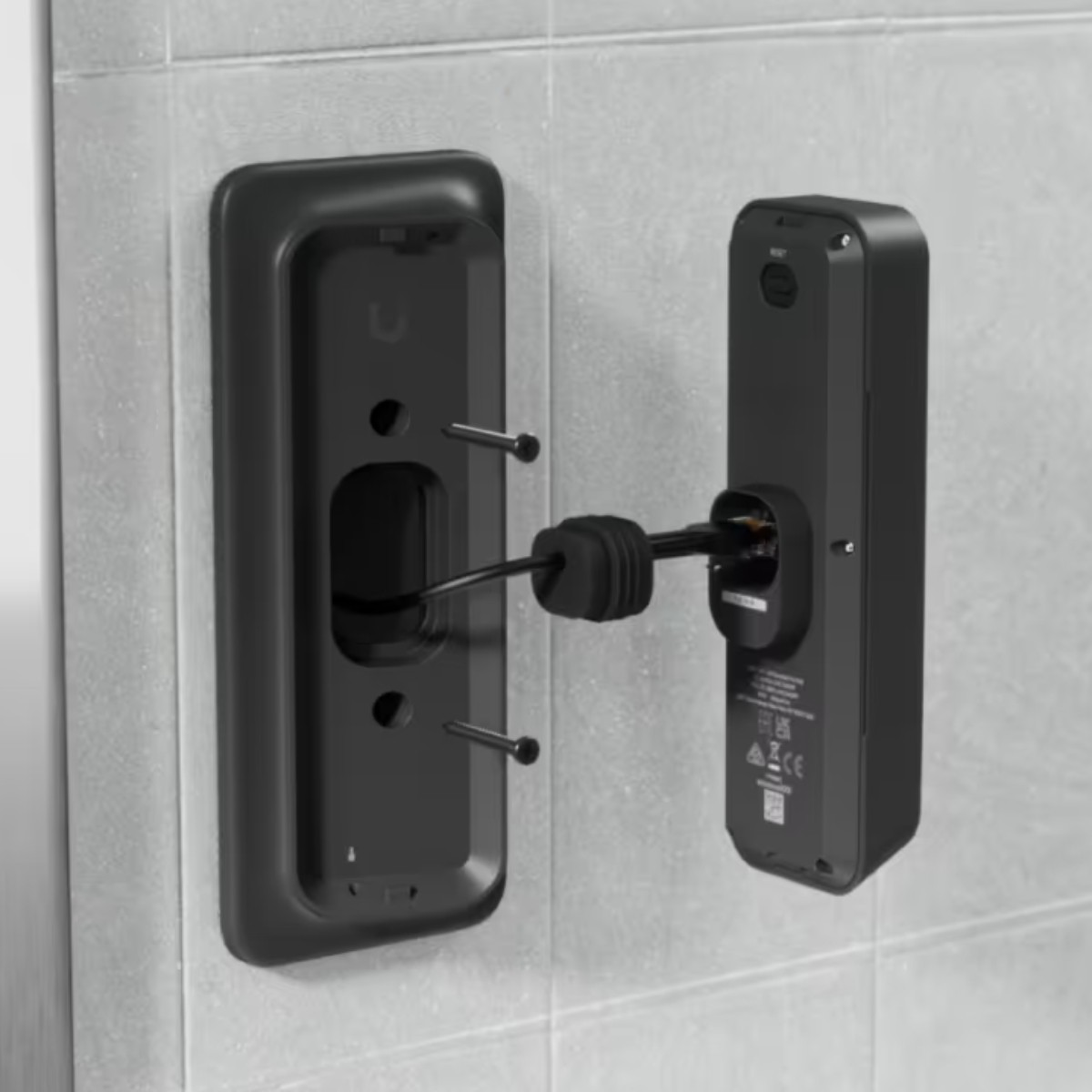 Een zwart apparaat wordt op een betegelde muur gemonteerd, kabels worden aangesloten.