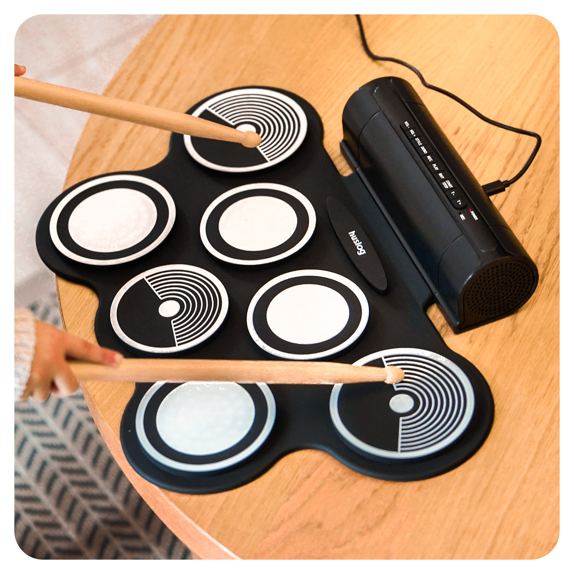 Czarna, przenośna mata perkusyjna z pałeczkami i jednostką głośnikową.