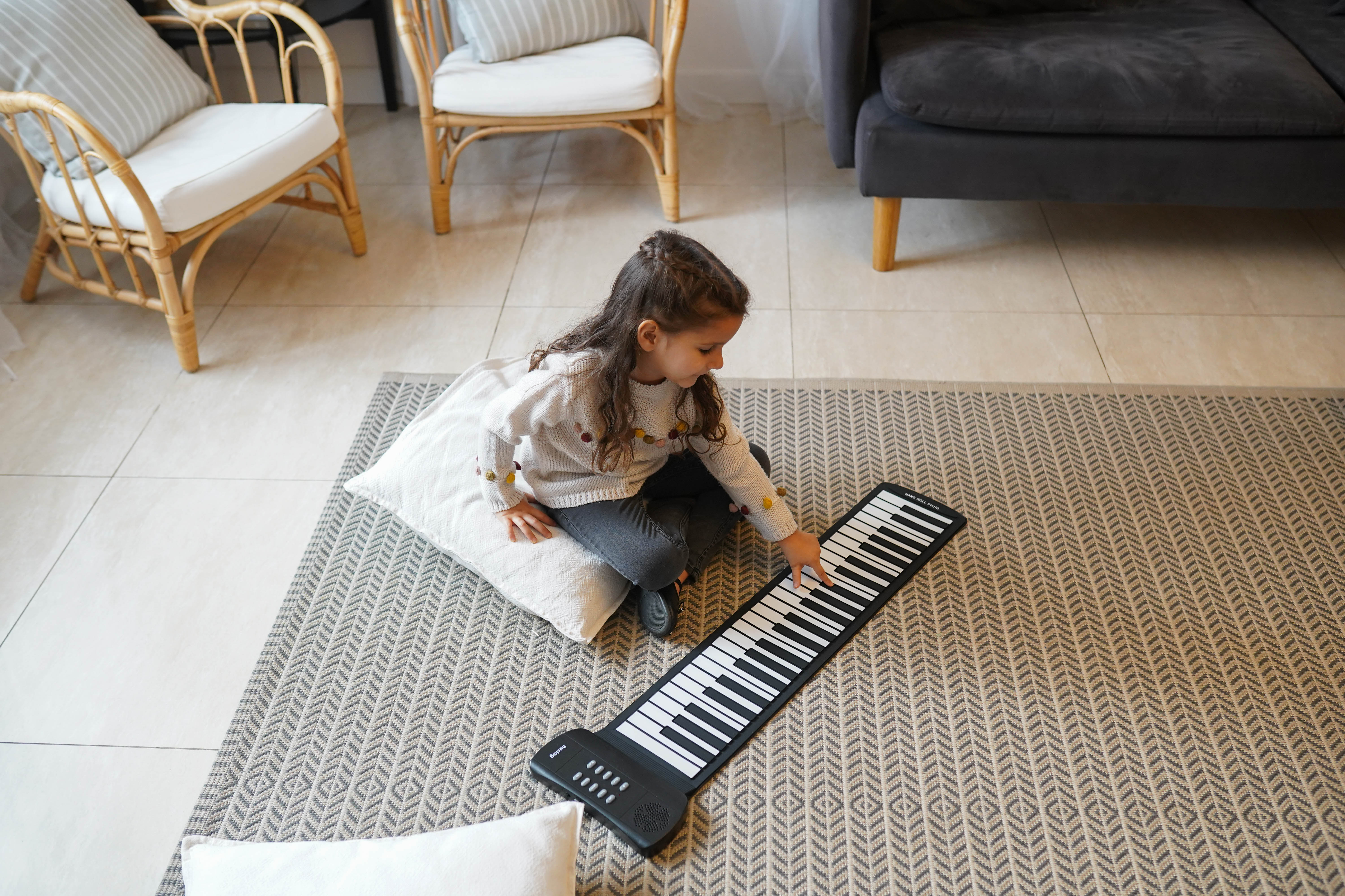 Mała dziewczynka gra na zwijanym keyboardzie w salonie.