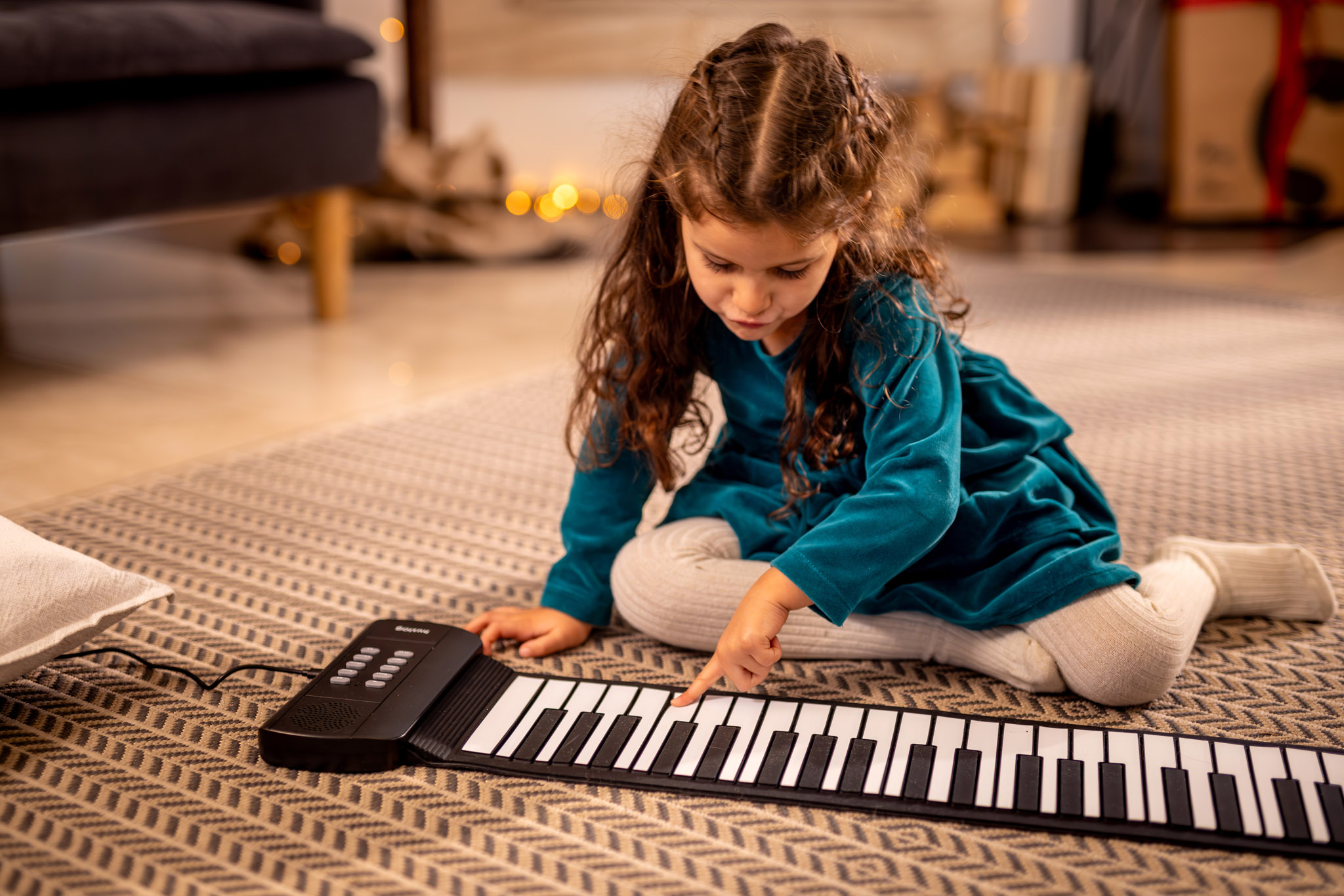 Mała dziewczynka z długimi brązowymi włosami gra na czarnej klawiaturze.