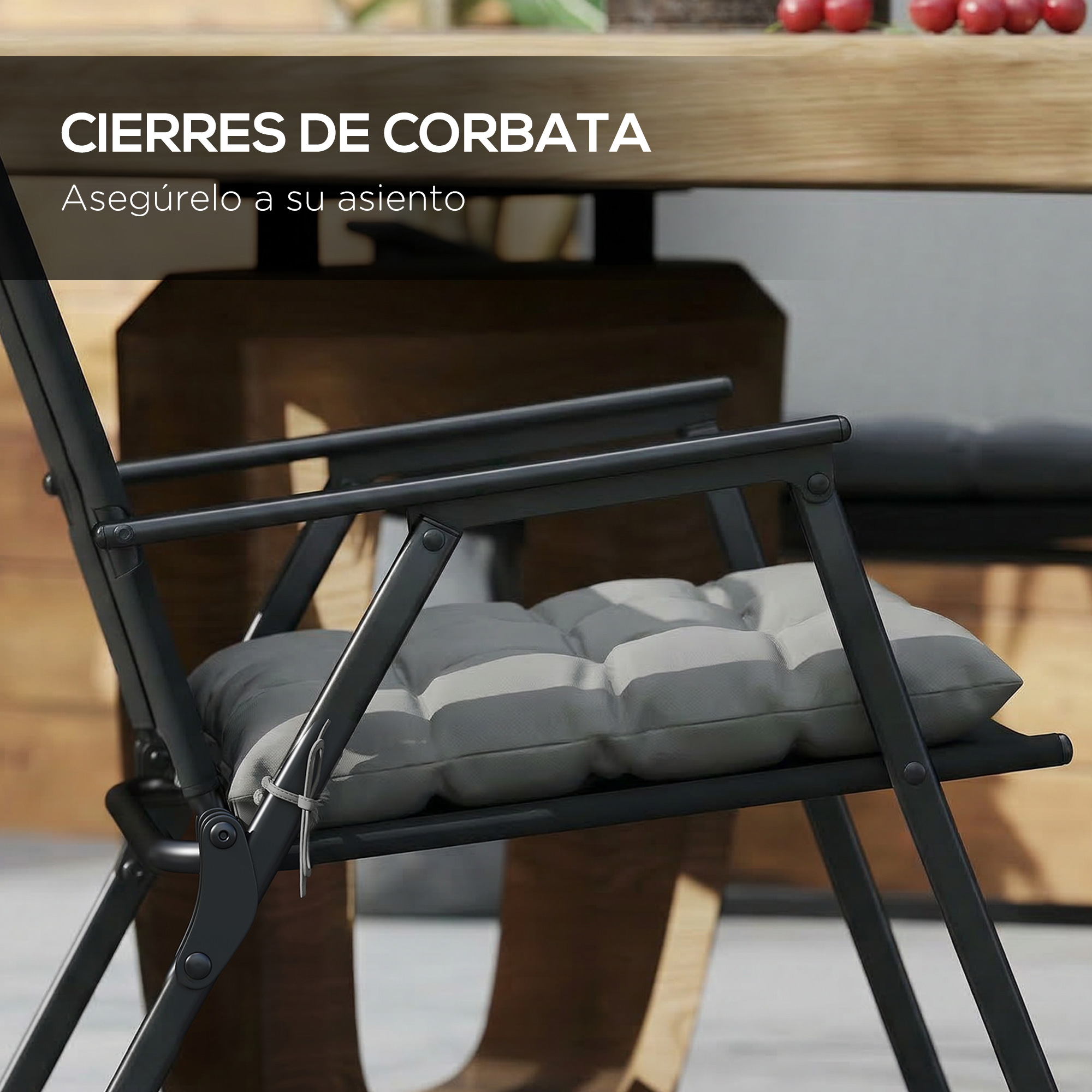 Silla plegable negra con cojín gris y mesa de madera al fondo.