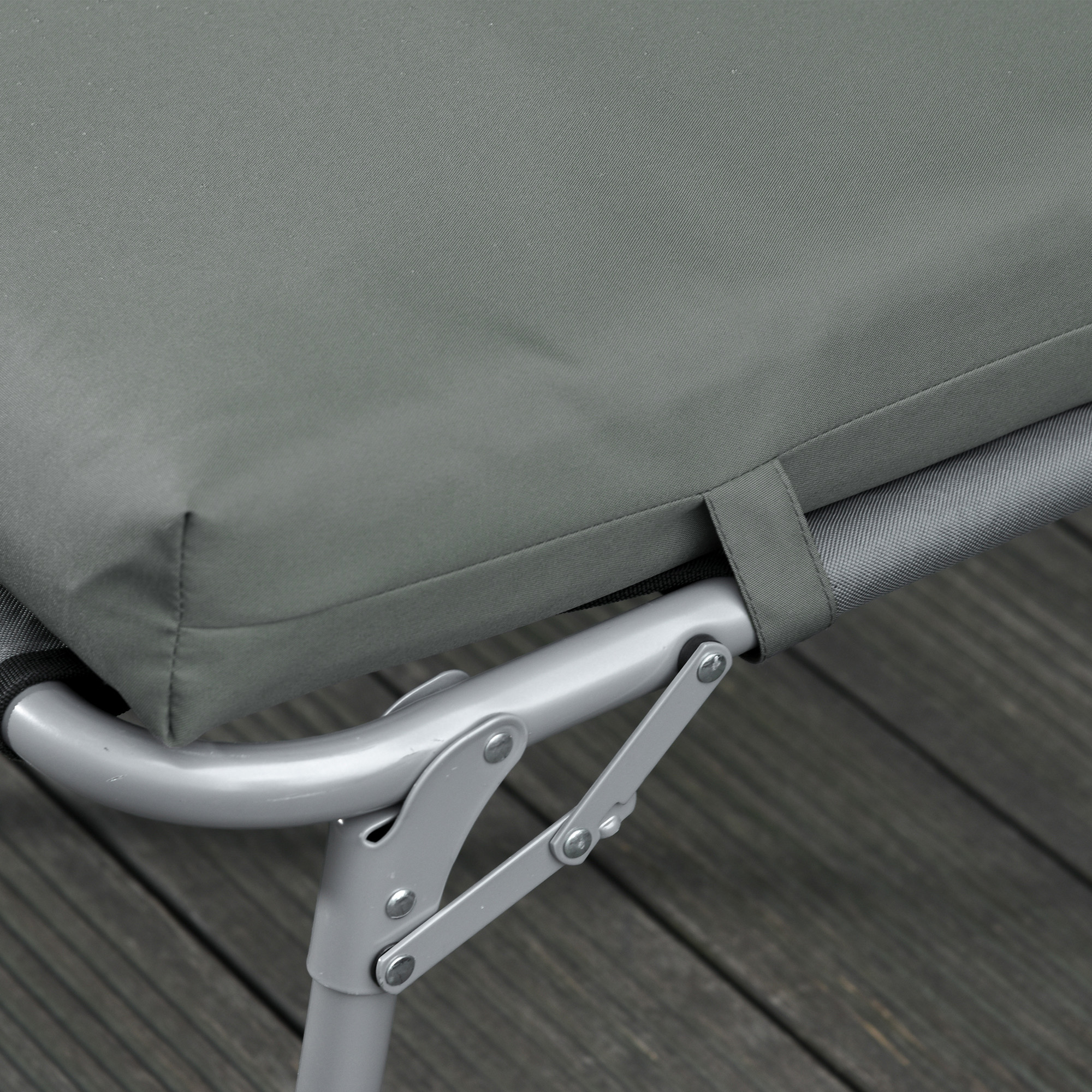 Cuscino grigio su telaio metallico con rivetti, su assi di legno.