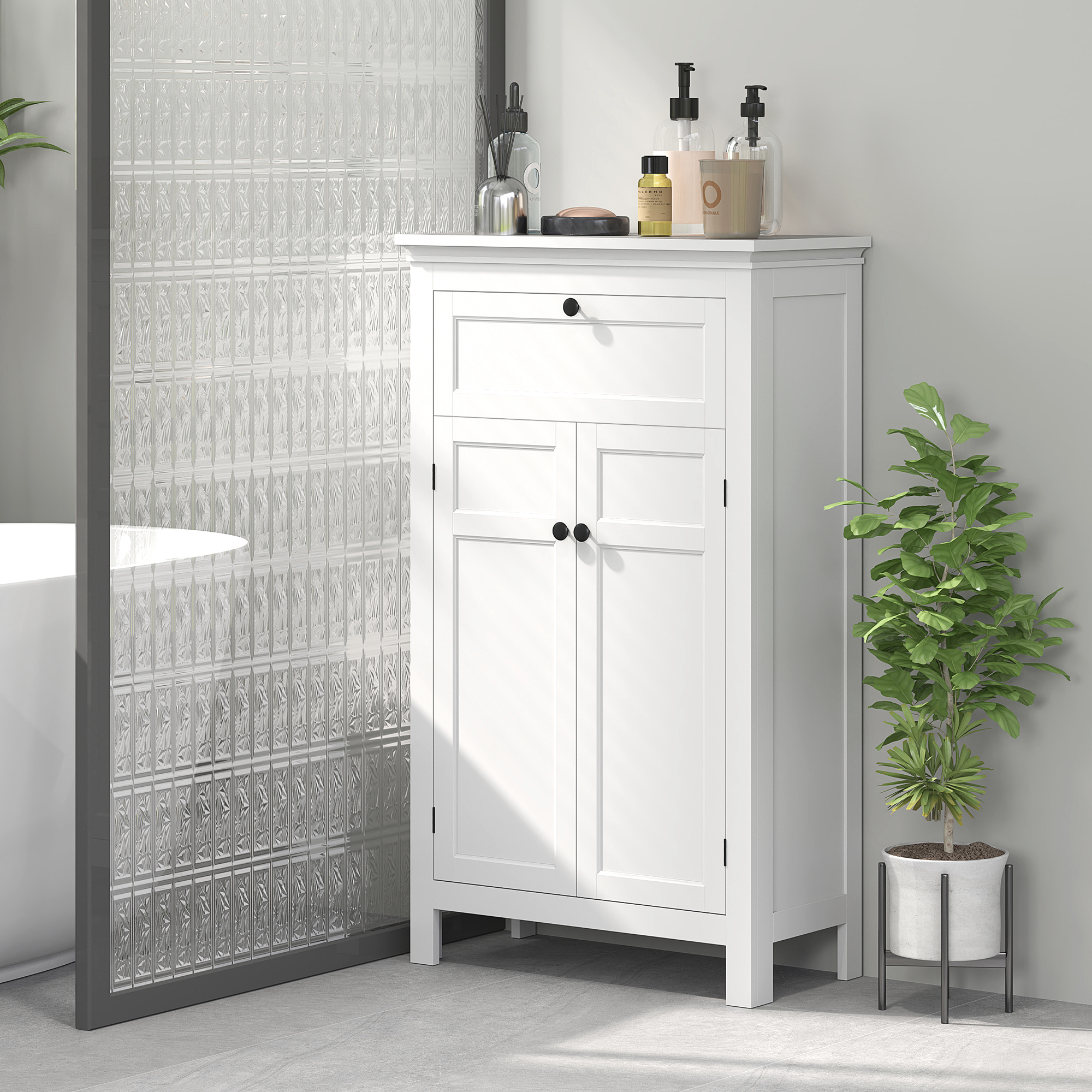 Un mueble de baño blanco junto a una pared de cristal y una planta.