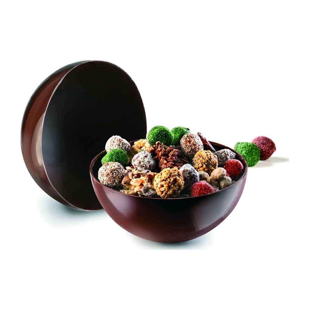 Bol en chocolat rempli de chocolats assortis et de noix, à côté d'une demi-sphère en chocolat.