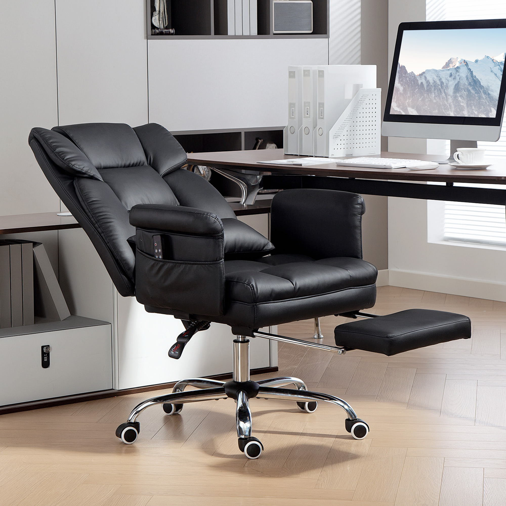 Una silla de oficina negra con reposapiés está frente a un escritorio con una computadora.