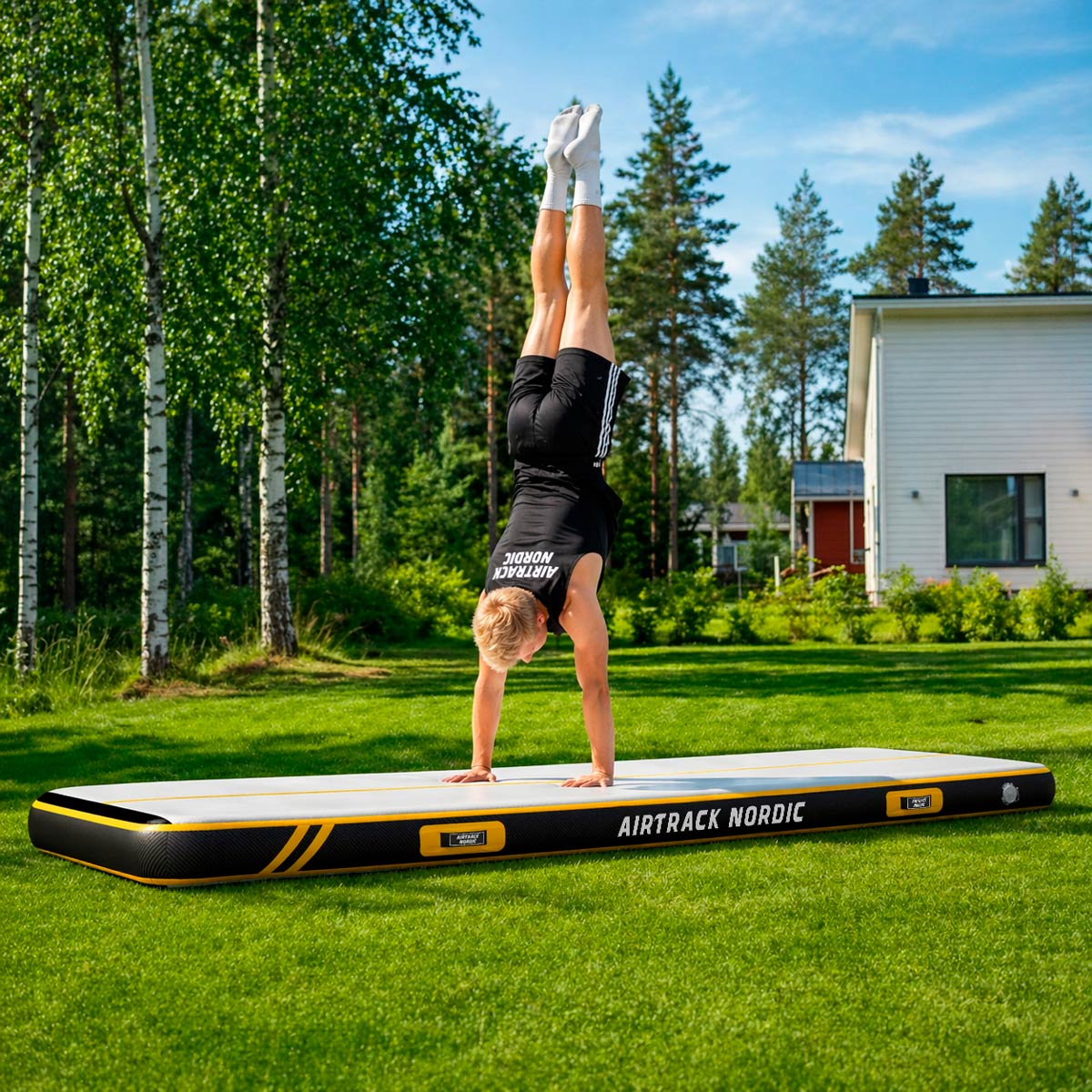 Ein Mann macht einen Handstand auf einer aufblasbaren Matte im Garten.