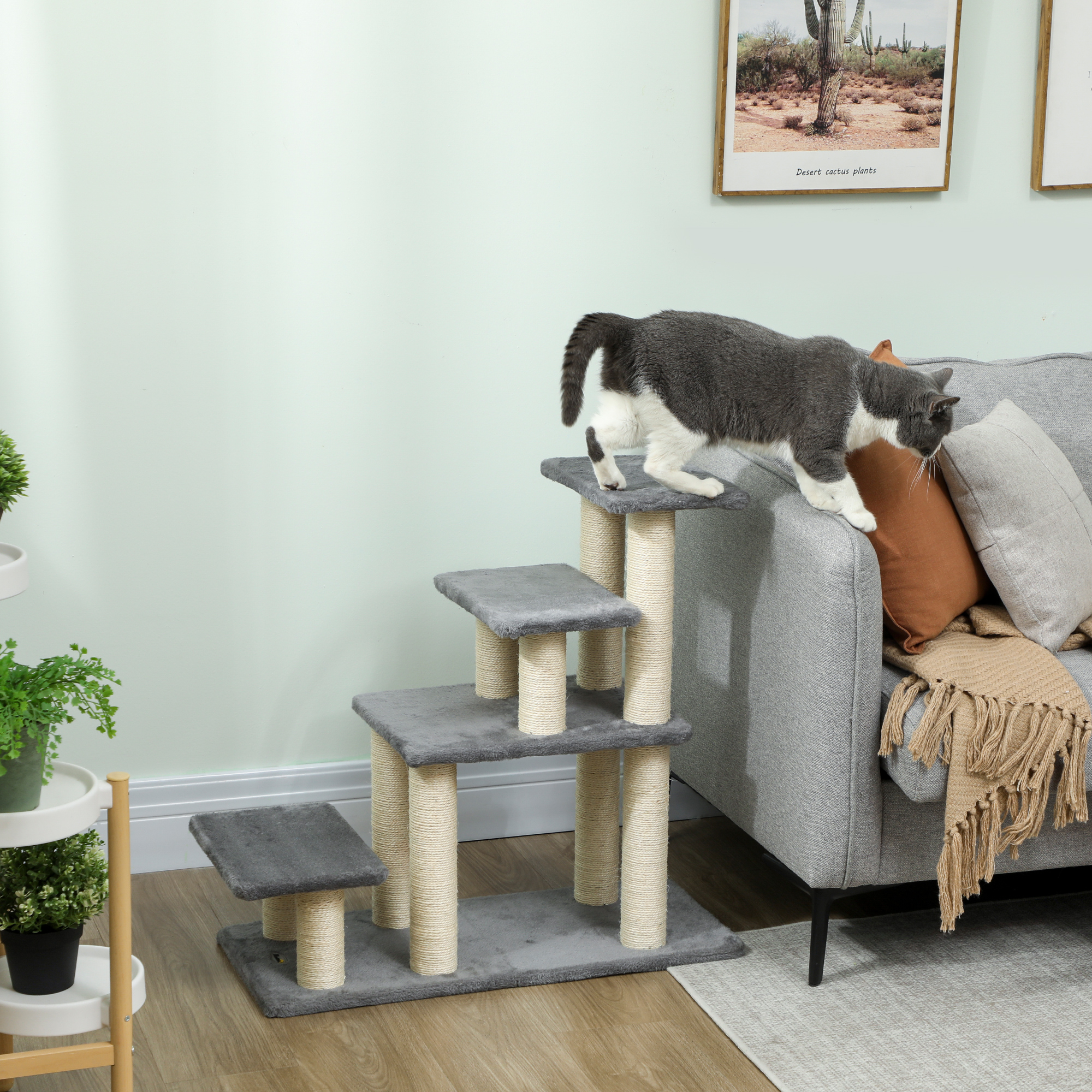Un gato trepa a un rascador gris de varios niveles junto a un sofá.