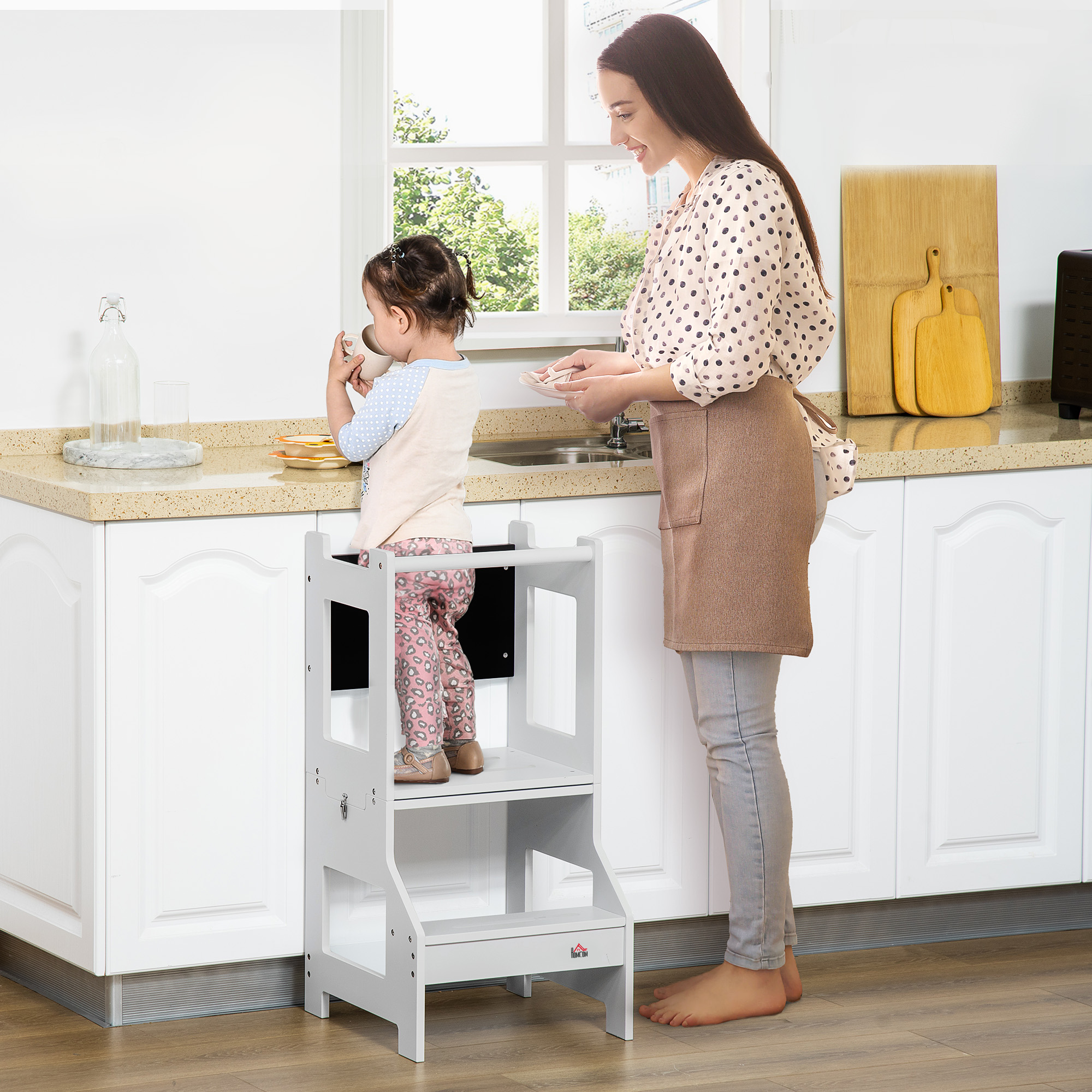 Una mujer y un niño en una cocina. El niño está en un taburete y bebe.