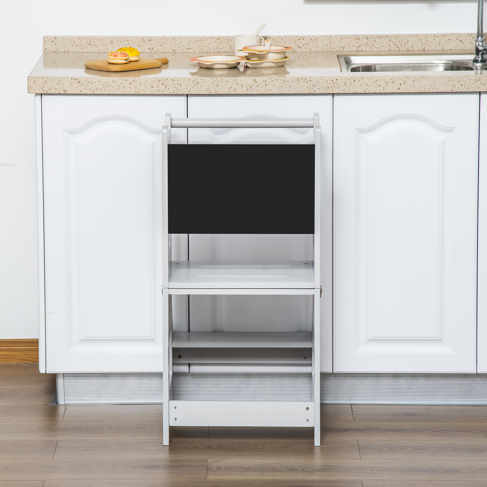 Un taburete blanco se encuentra frente a gabinetes de cocina blancos con fregadero y grifo.
