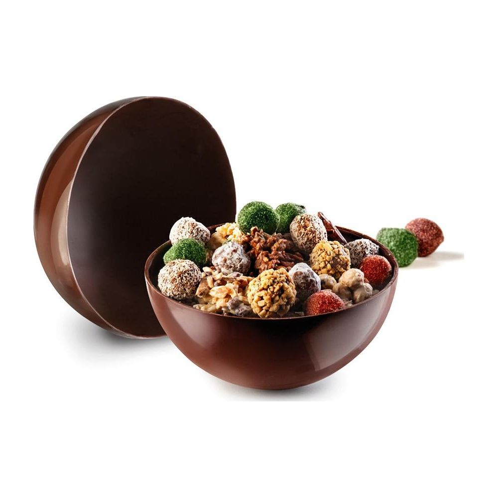 Bol en chocolat rempli de noix et de pralines, à côté d'une demi-sphère en chocolat.