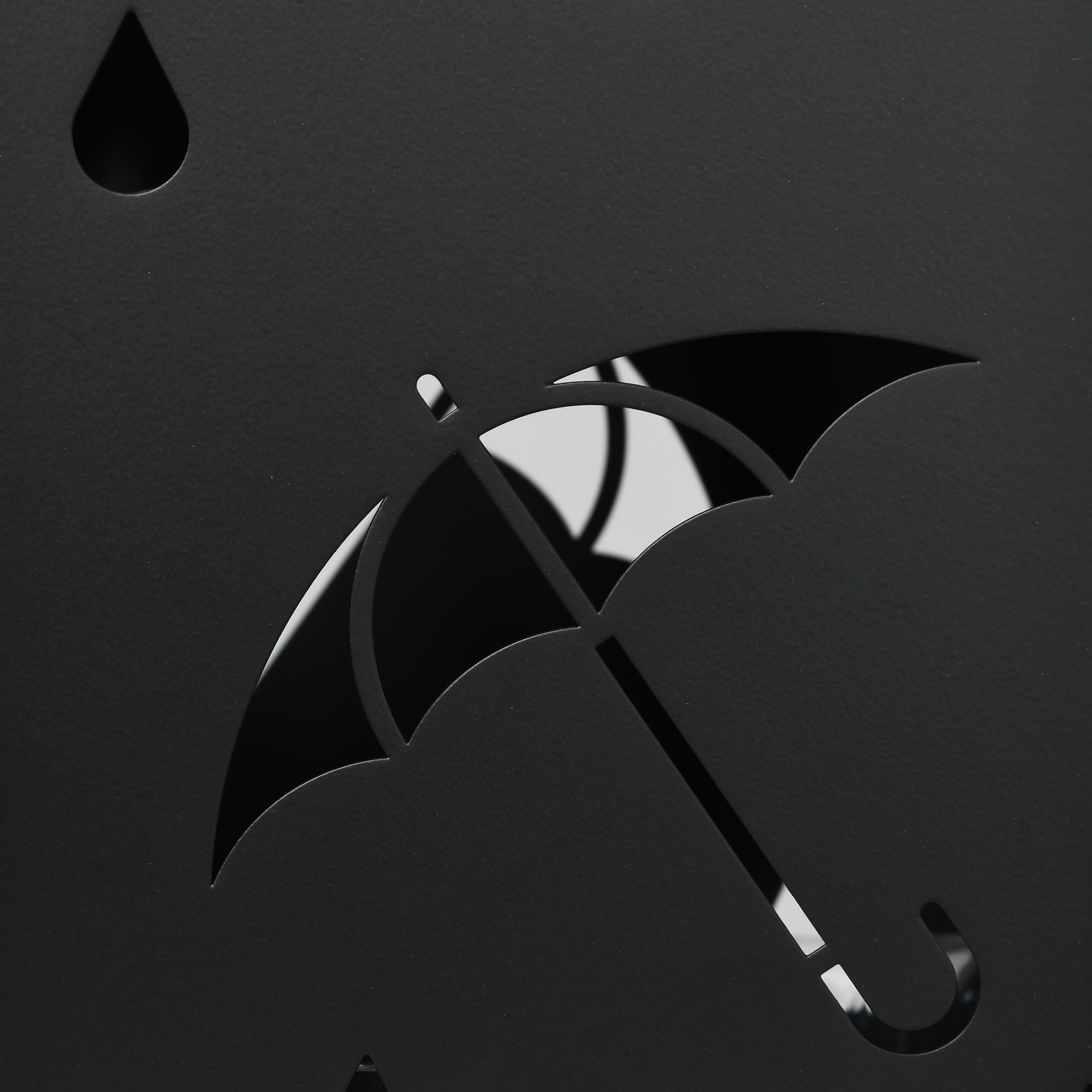Un relieve negro con gotas de lluvia recortadas y un paraguas.