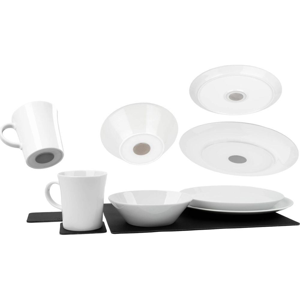 Piatti, ciotole e tazze in ceramica bianca su tovagliette nere.
