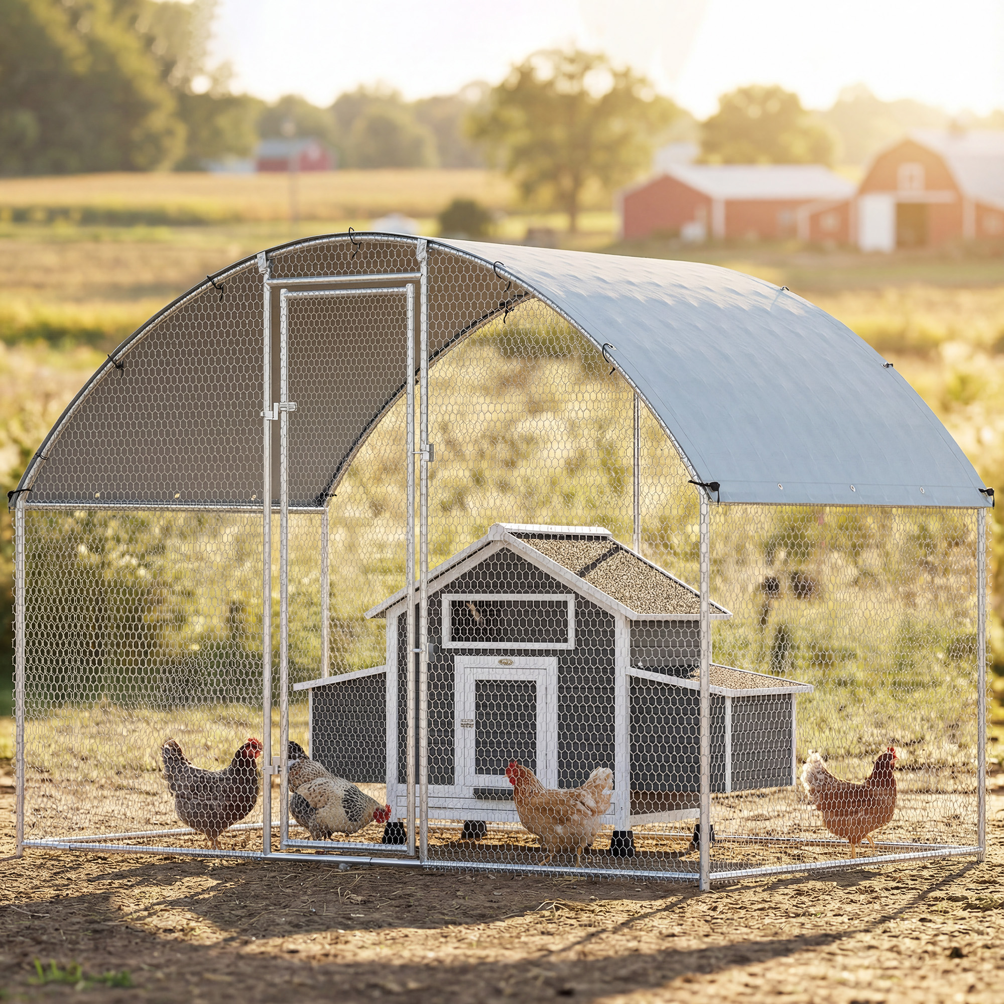 Gallinero con cuatro gallinas en un campo con casas de campo al fondo.