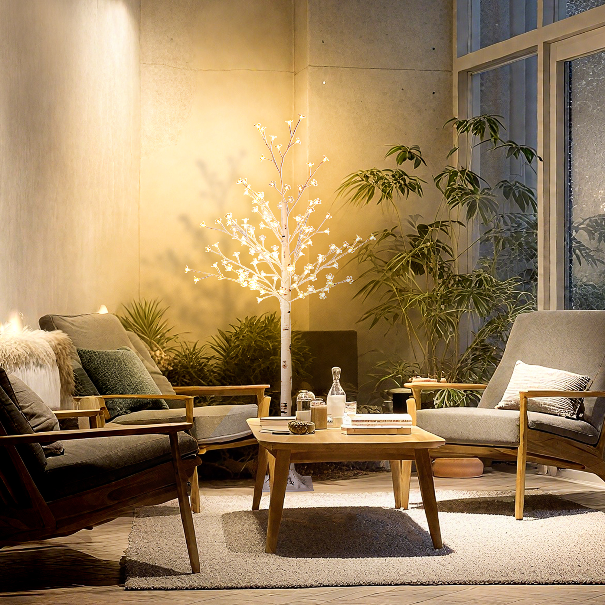 Un árbol decorativo iluminado se alza entre dos sillas y plantas. Una mesa de centro está delante.