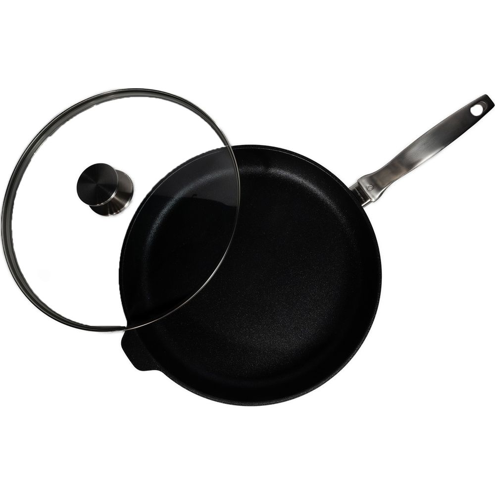 Une poêle noire avec couvercle en verre et manche argenté est vue de dessus.