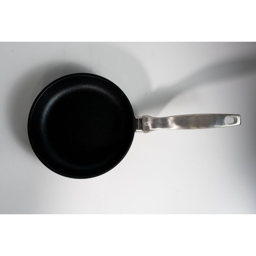 Poêle noire avec un long manche argenté sur fond blanc avec une ombre.