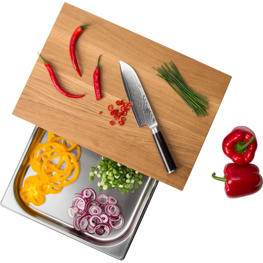 Tabla de cortar de madera con cuchillo, chiles, cebollas, pimientos y cebollino.