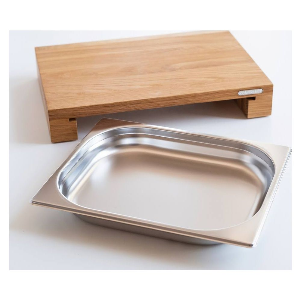 Un soporte de tabla de cortar de madera sobre una sartén rectangular de metal.