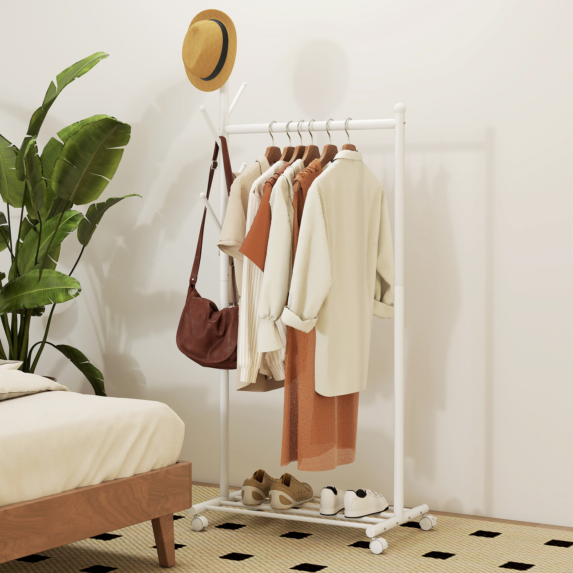 Perchero con ropa, bolso, sombrero y plantas junto a una cama.