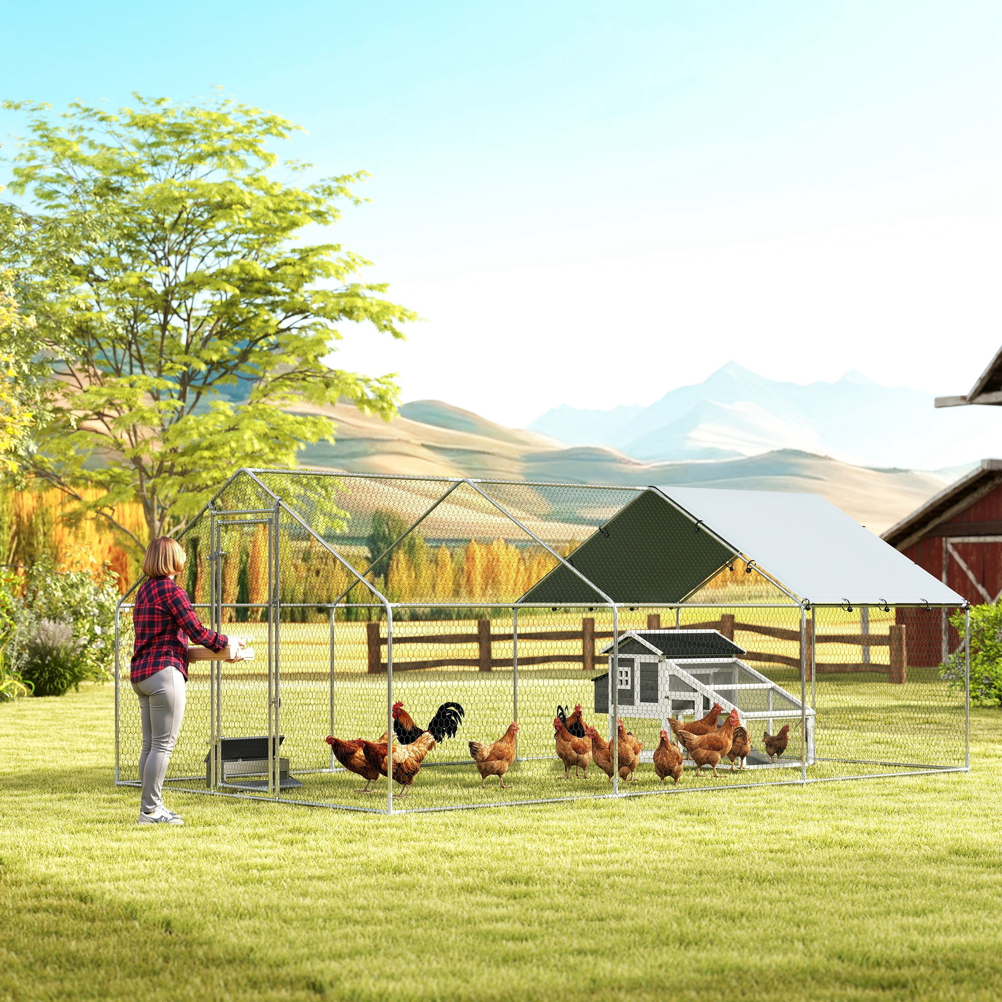 Una mujer alimentando pollos en un gran gallinero al aire libre con montañas al fondo.
