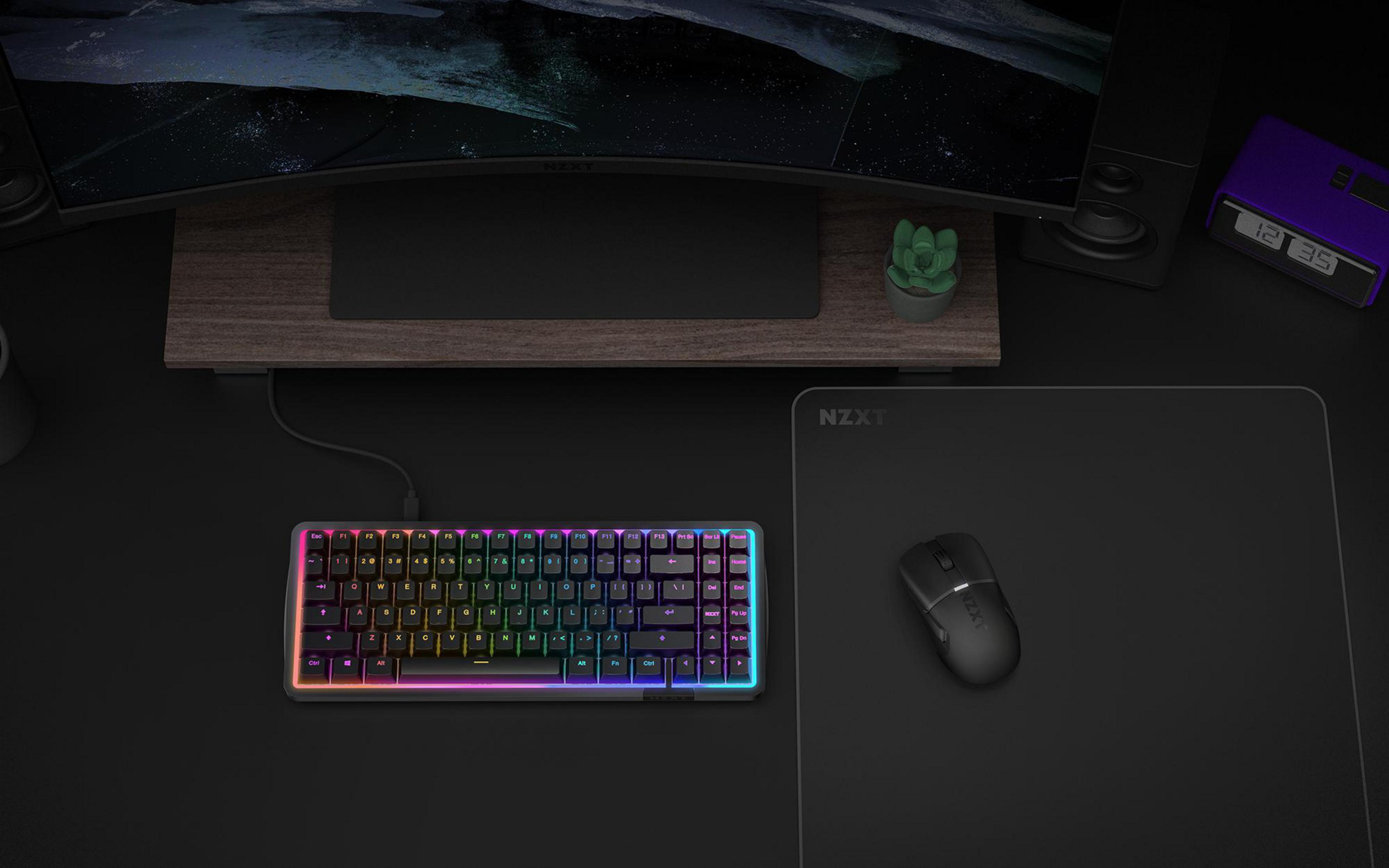A black NZXT mouse and a colorful RGB keyboard on a desk.