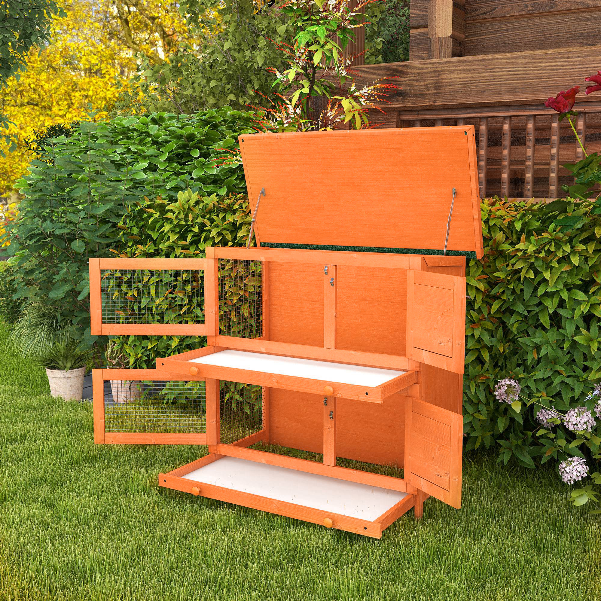 Una conejera de madera naranja con puertas y ventanas abiertas sobre césped verde.