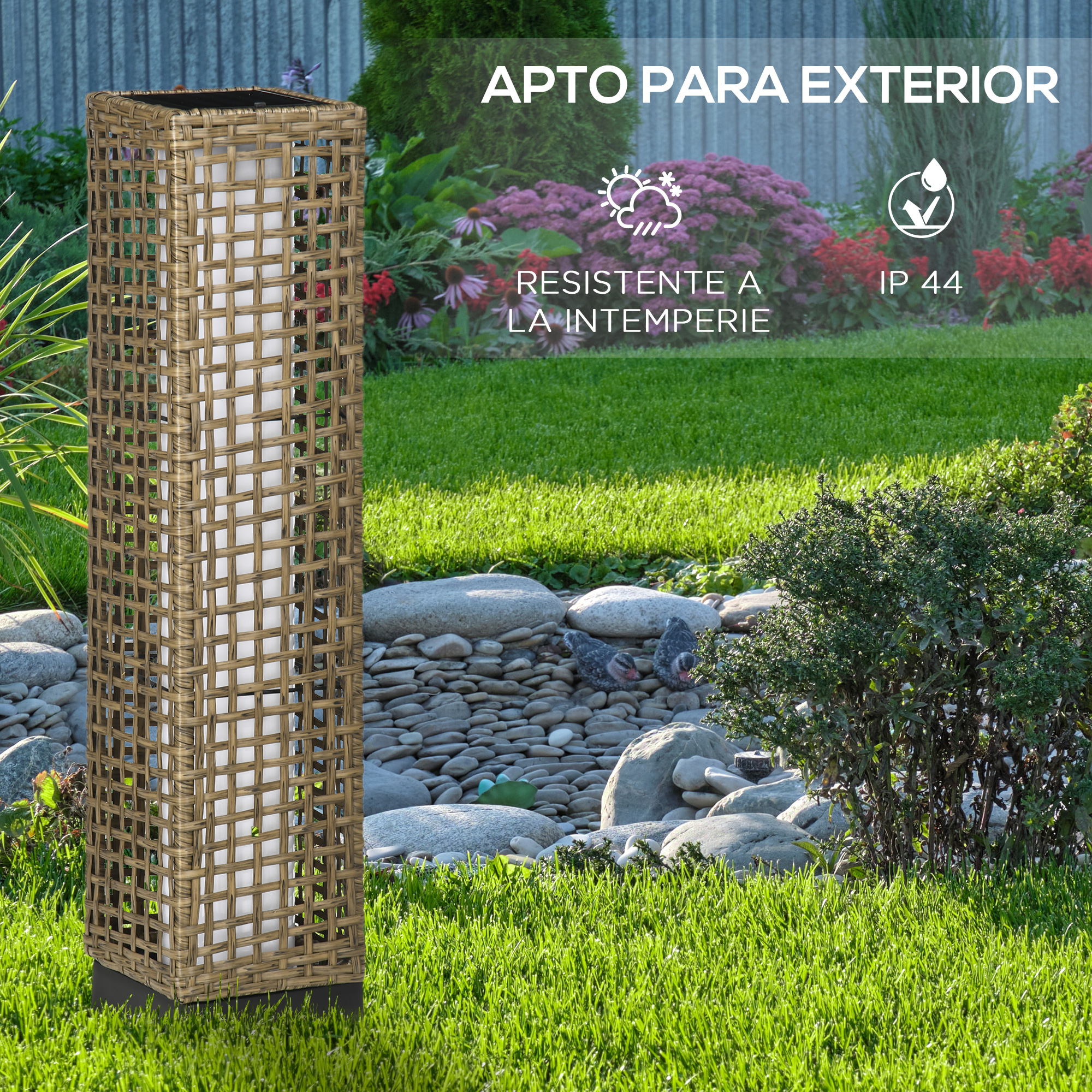 Un poste de lámpara de mimbre rectangular para exteriores se encuentra en el césped junto a un lecho de jardín de piedra.