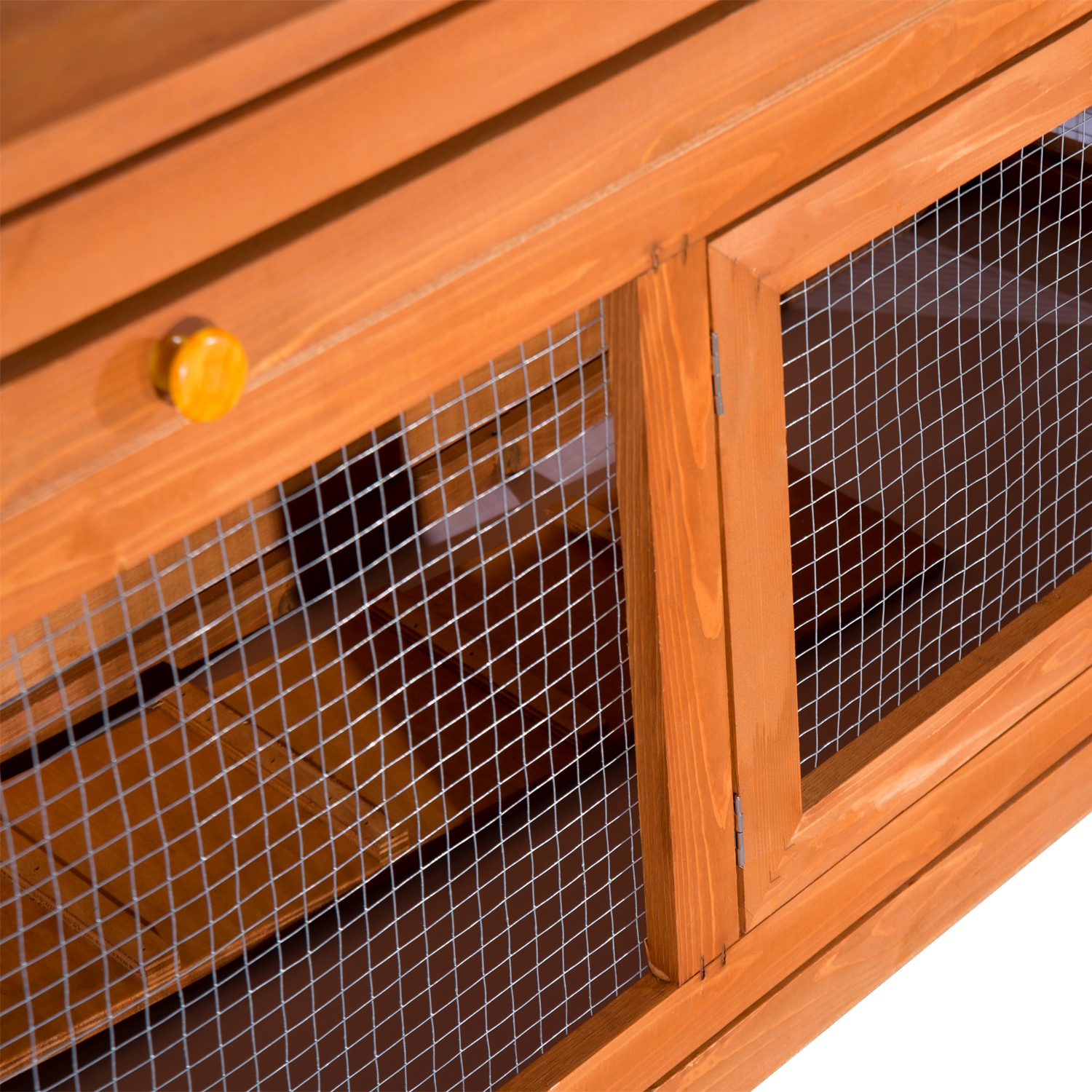 Primer plano de una conejera de madera con puertas de malla metálica y pomo amarillo.