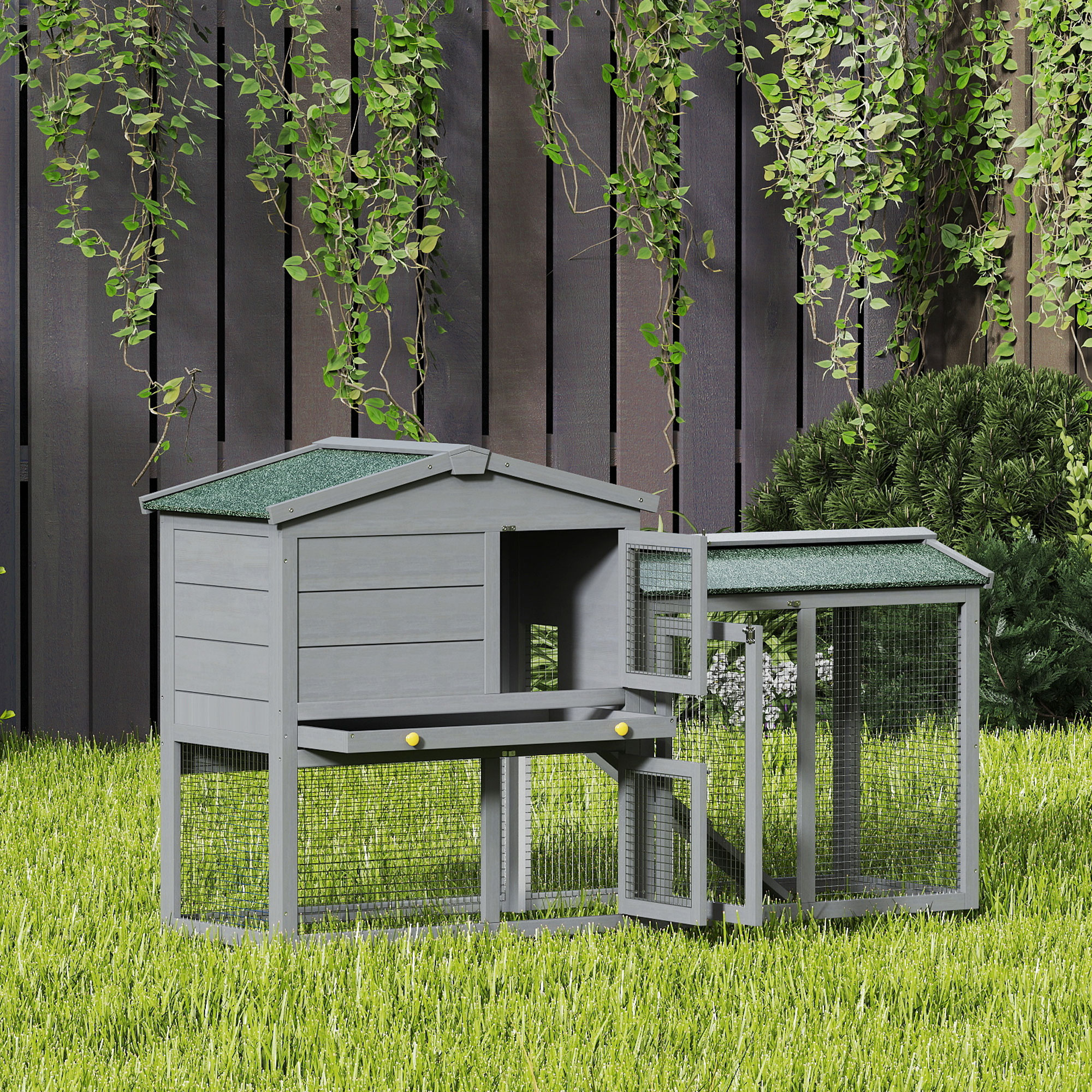 Una pajarera de madera gris con techos verdes, sobre césped verde.