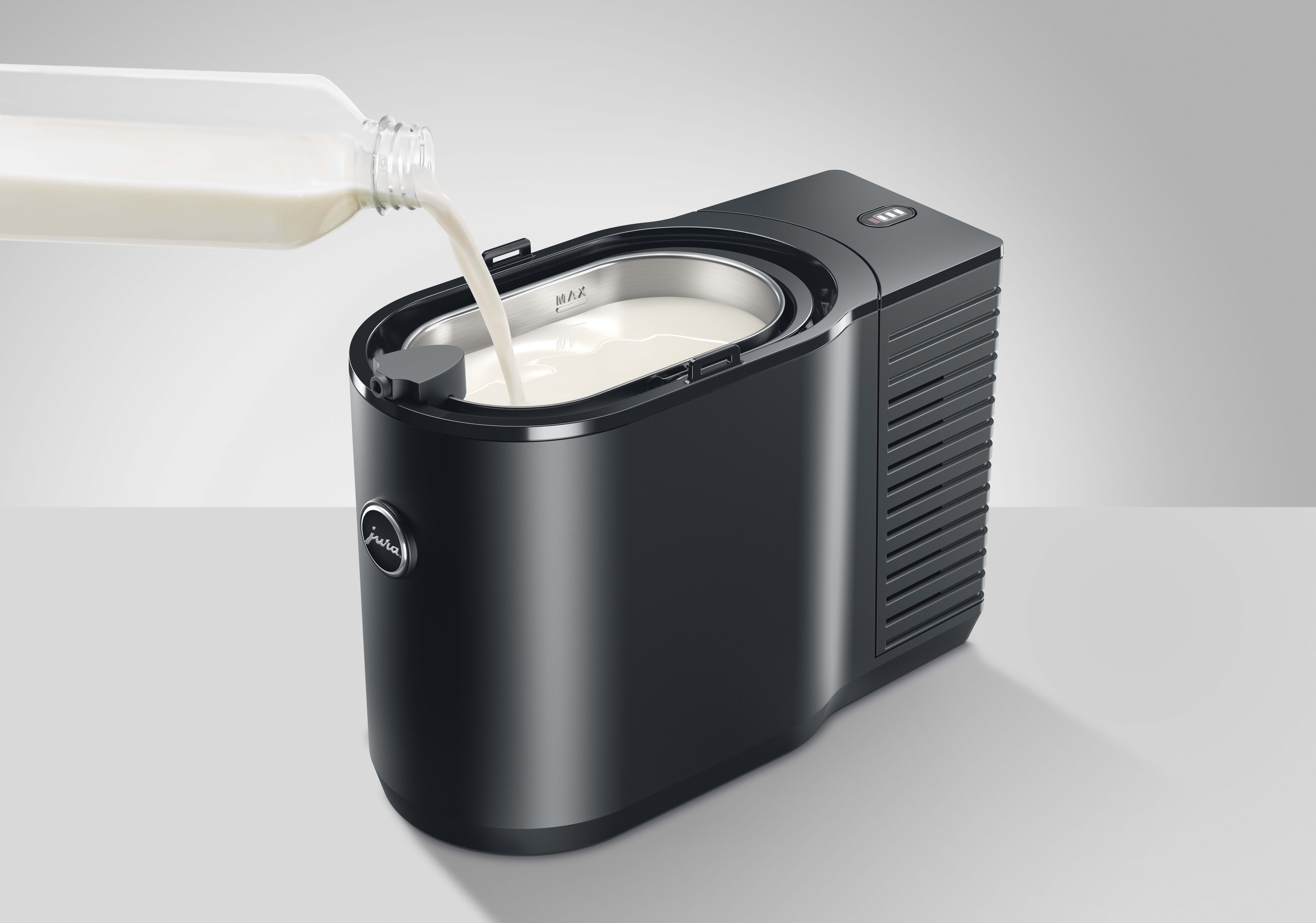 Il latte viene versato da una bottiglia di vetro in un contenitore per latte nero.