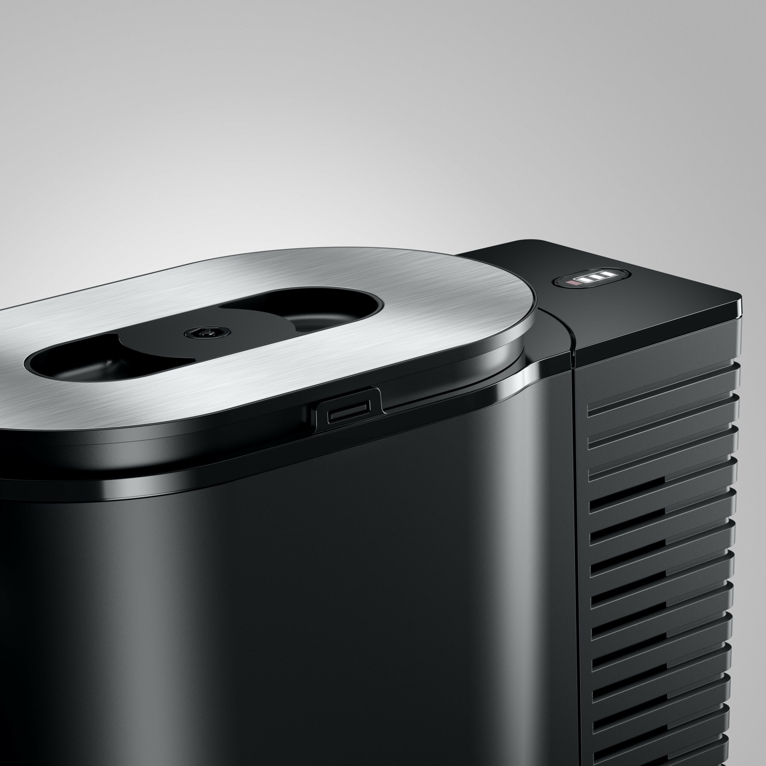Primo piano di un dispositivo nero con coperchio argentato e fessure di ventilazione.