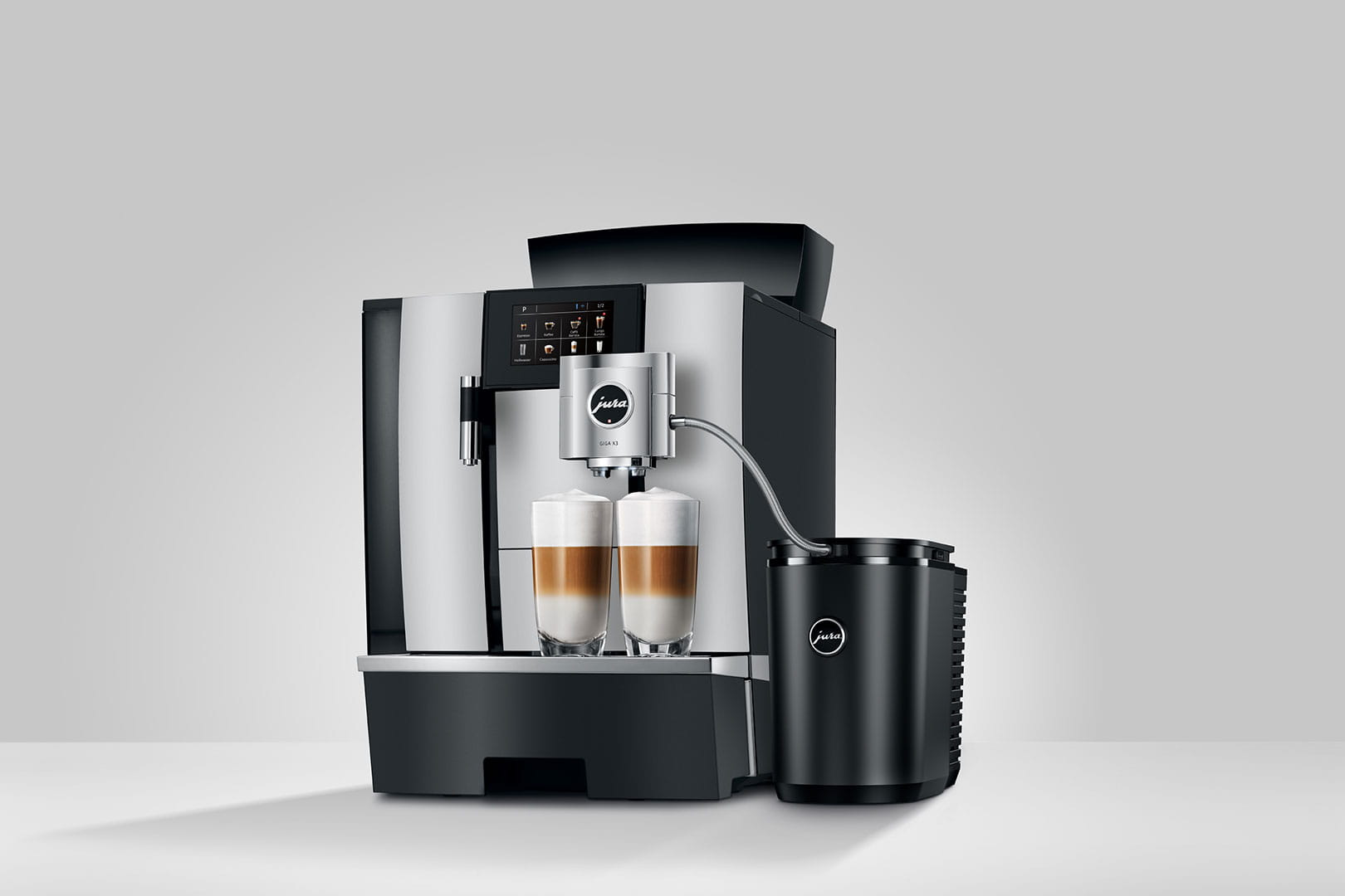 Una macchina da caffè Jura argentata e nera con due bicchieri di latte macchiato.