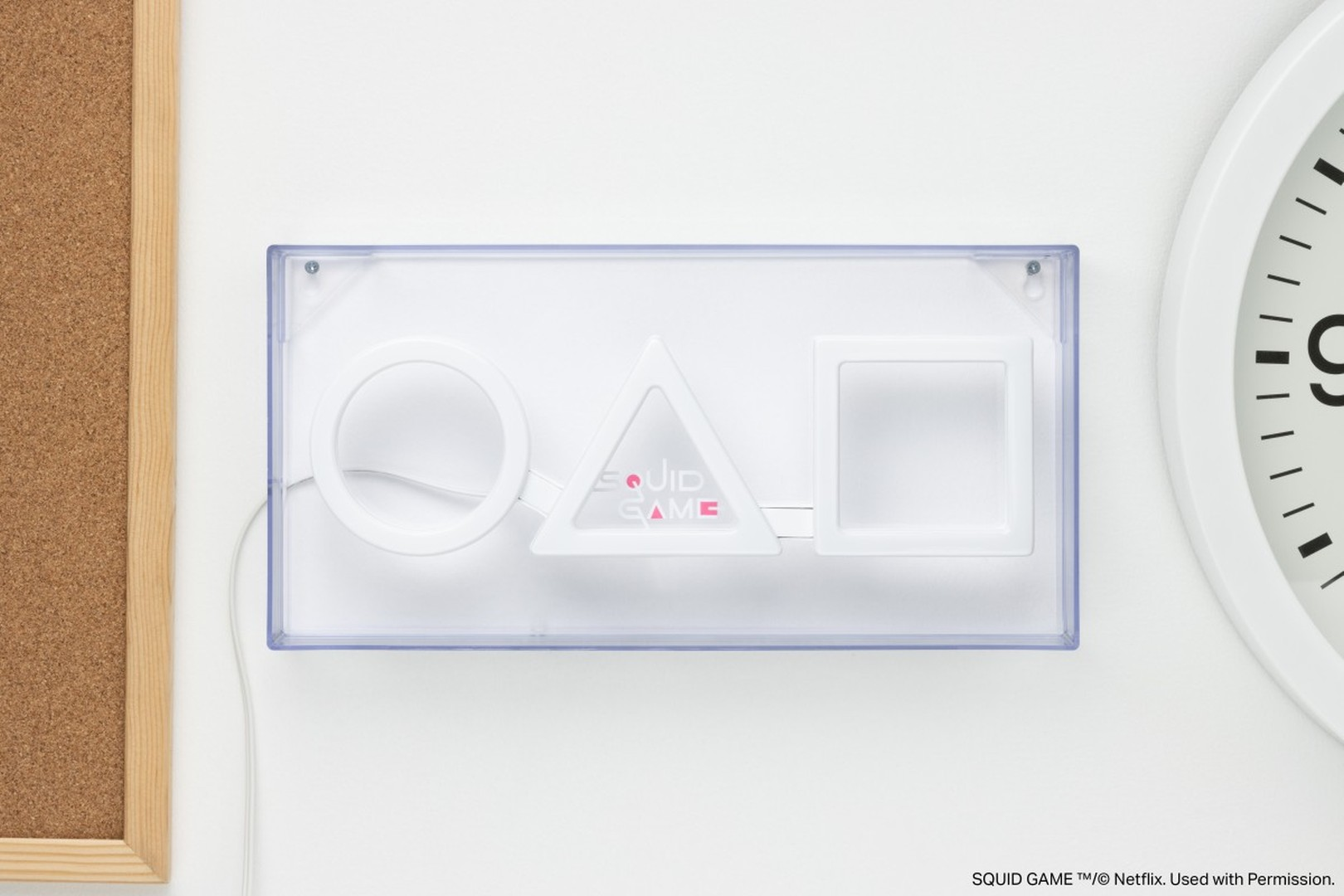 Lampa z symbolami "Squid Game" w kształcie koła, trójkąta i kwadratu na białym tle.