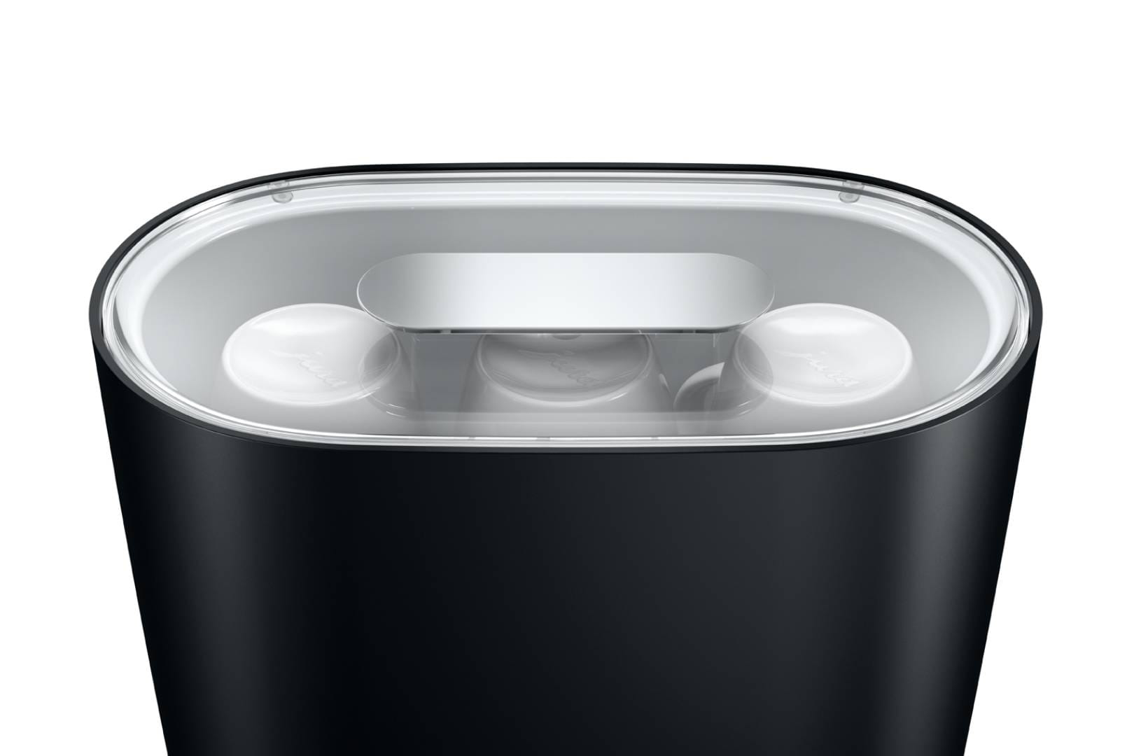 Un contenitore nero con coperchio trasparente, tre capsule bianche all'interno.
