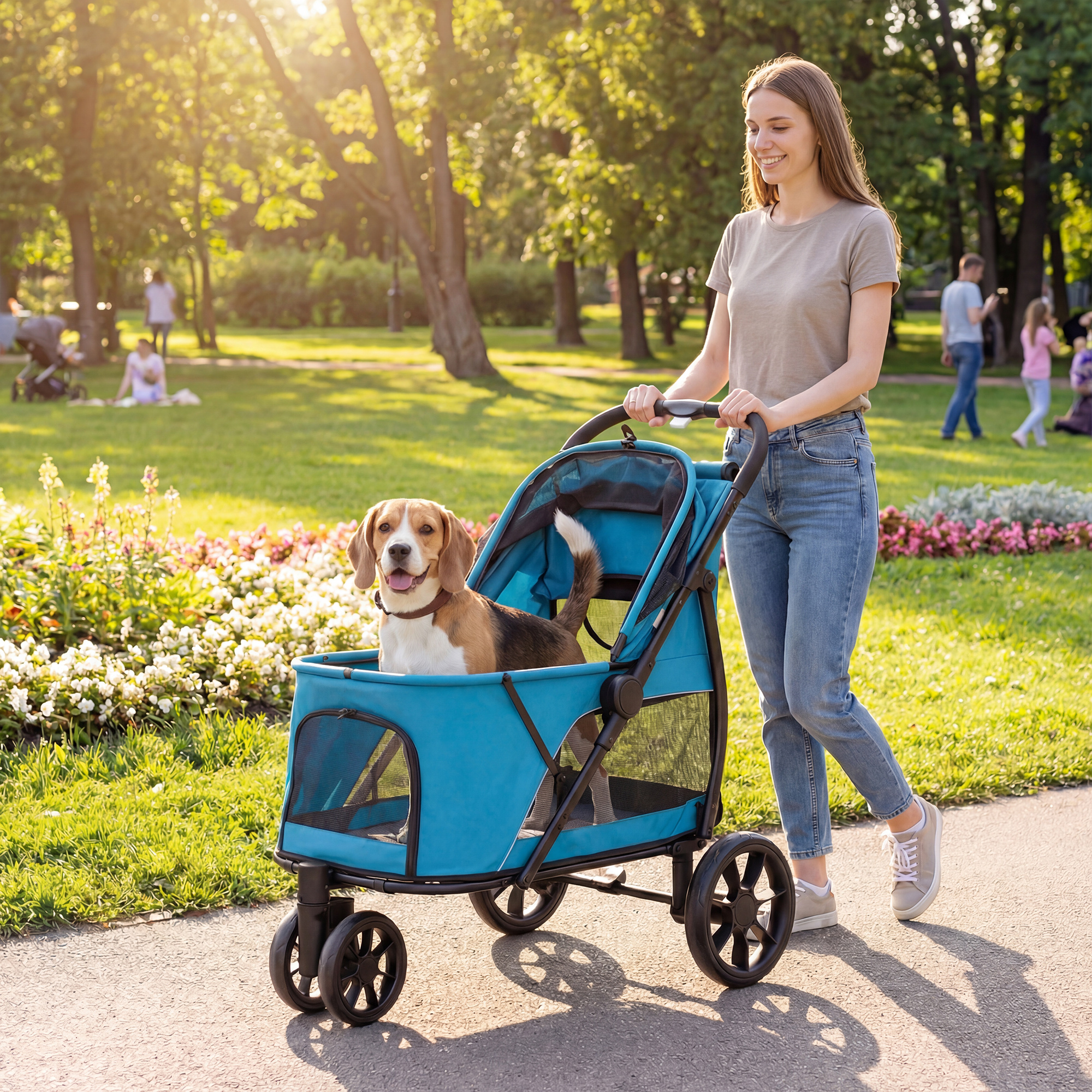 Una mujer empuja un beagle en un cochecito azul por un parque soleado con gente.