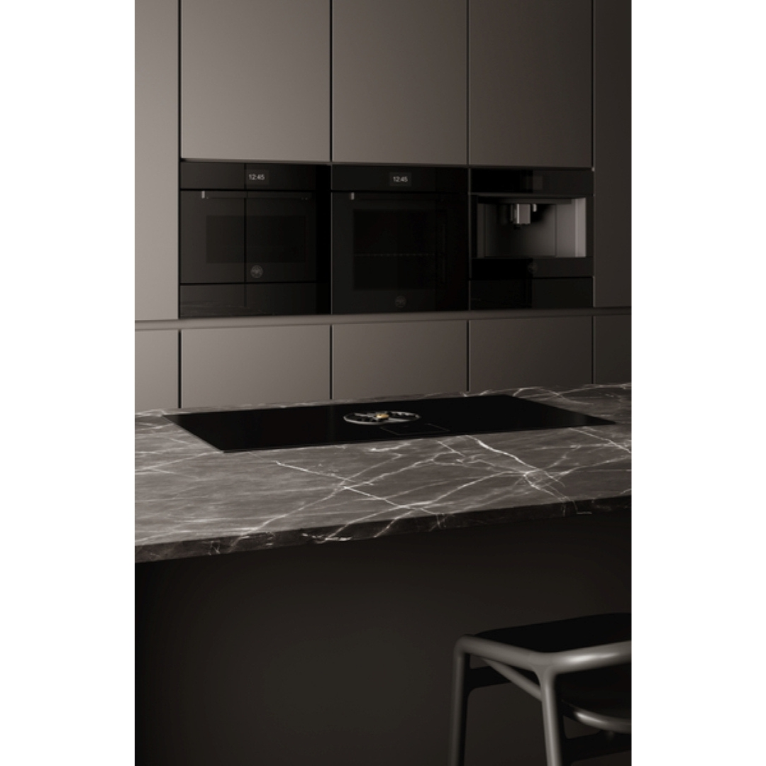 Cucina moderna con piano di lavoro in marmo, piano cottura a induzione e elettrodomestici.