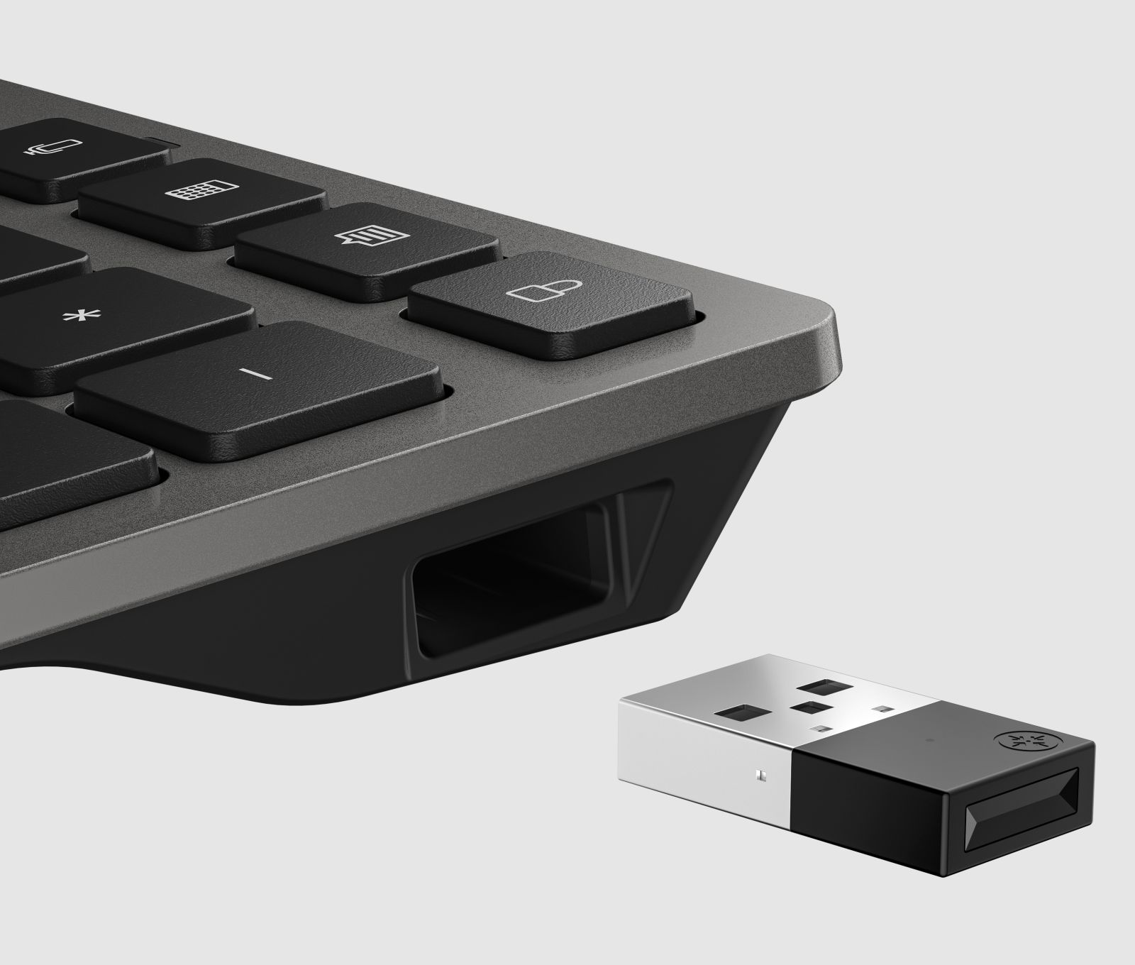 Een zwarte USB-dongle ligt op een grijze ondergrond naast een deel van een zwart toetsenbord.