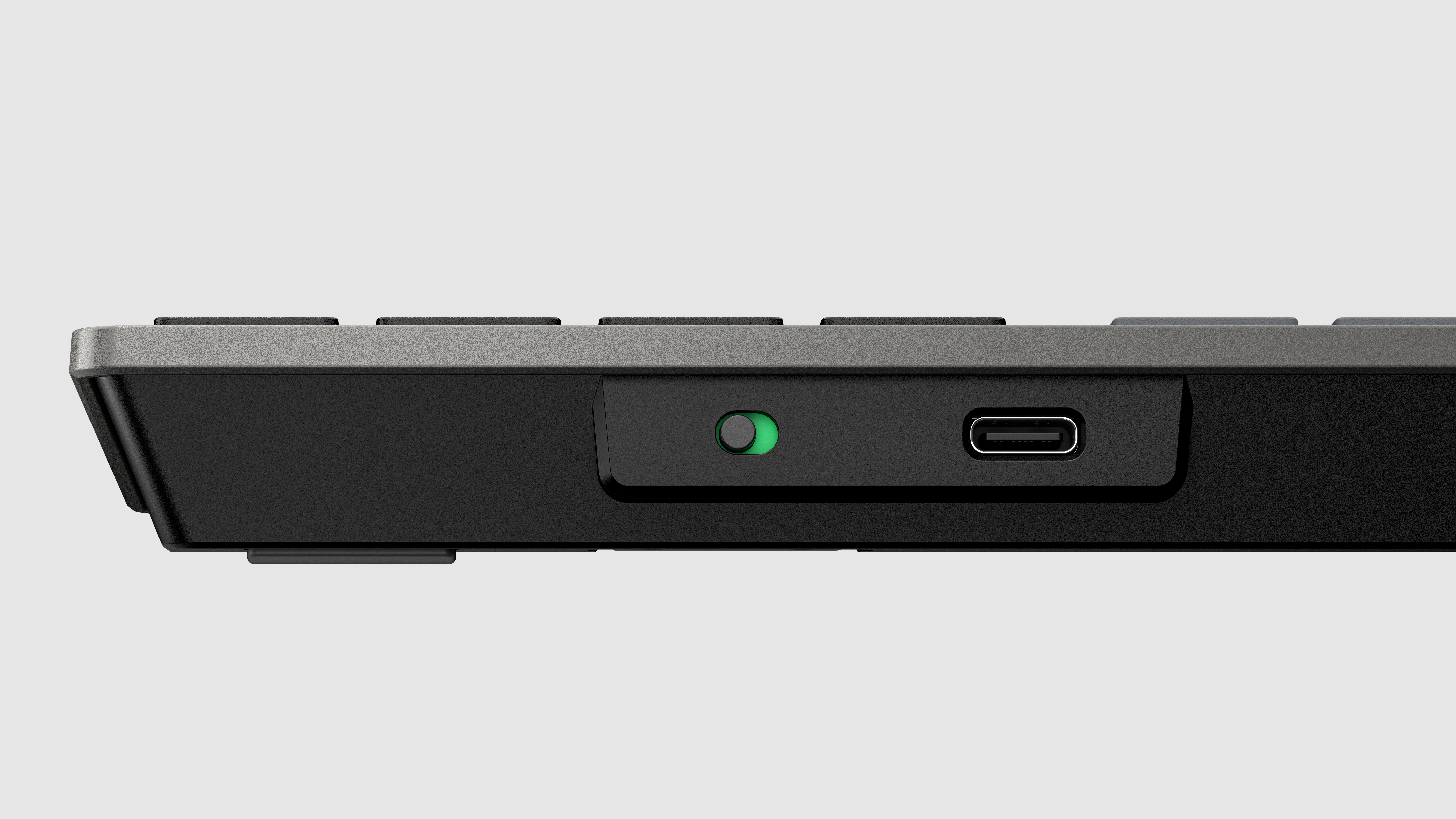 Close-up van de zijkant van een toetsenbord met USB-C poort en schakelaar.