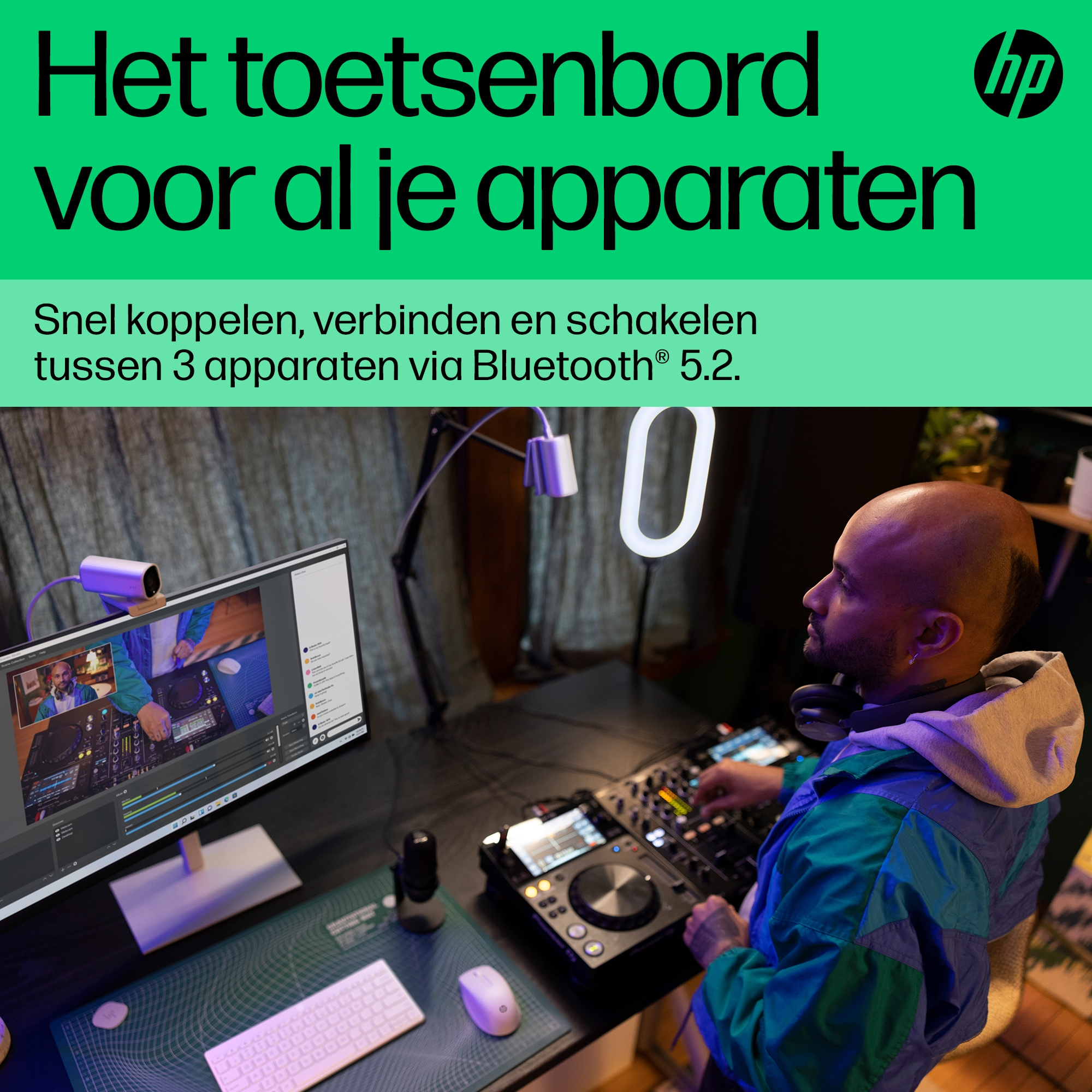 Ein Mann in einem bunten Jackett sitzt an einem Schreibtisch mit Geräten für Streaming.