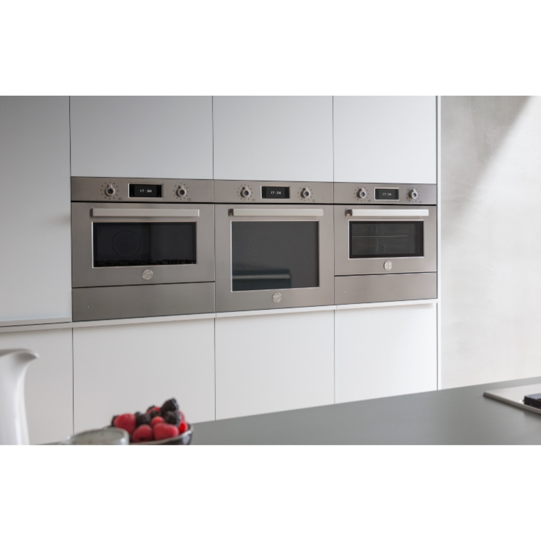 Tre forni da incasso in acciaio inossidabile in una cucina moderna, con display digitali.