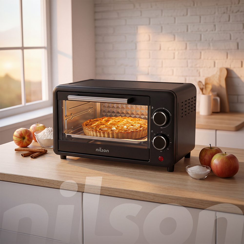 Un horno tostador negro con un pastel de manzana dentro. Manzanas y canela al lado.