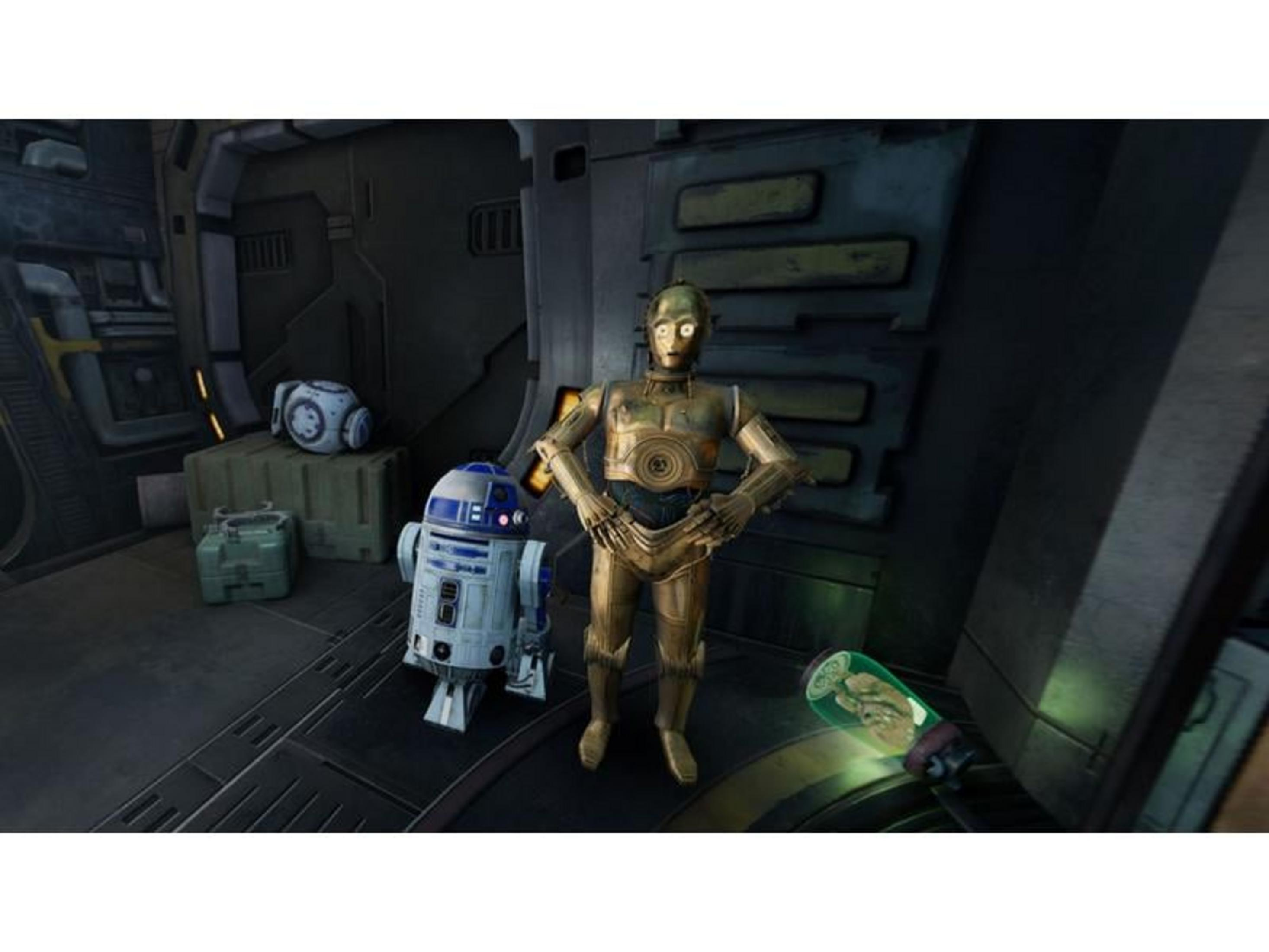 C-3PO und R2-D2 stehen neben Kisten. Ein kleiner Roboter und ein grünes Objekt sind zu sehen.