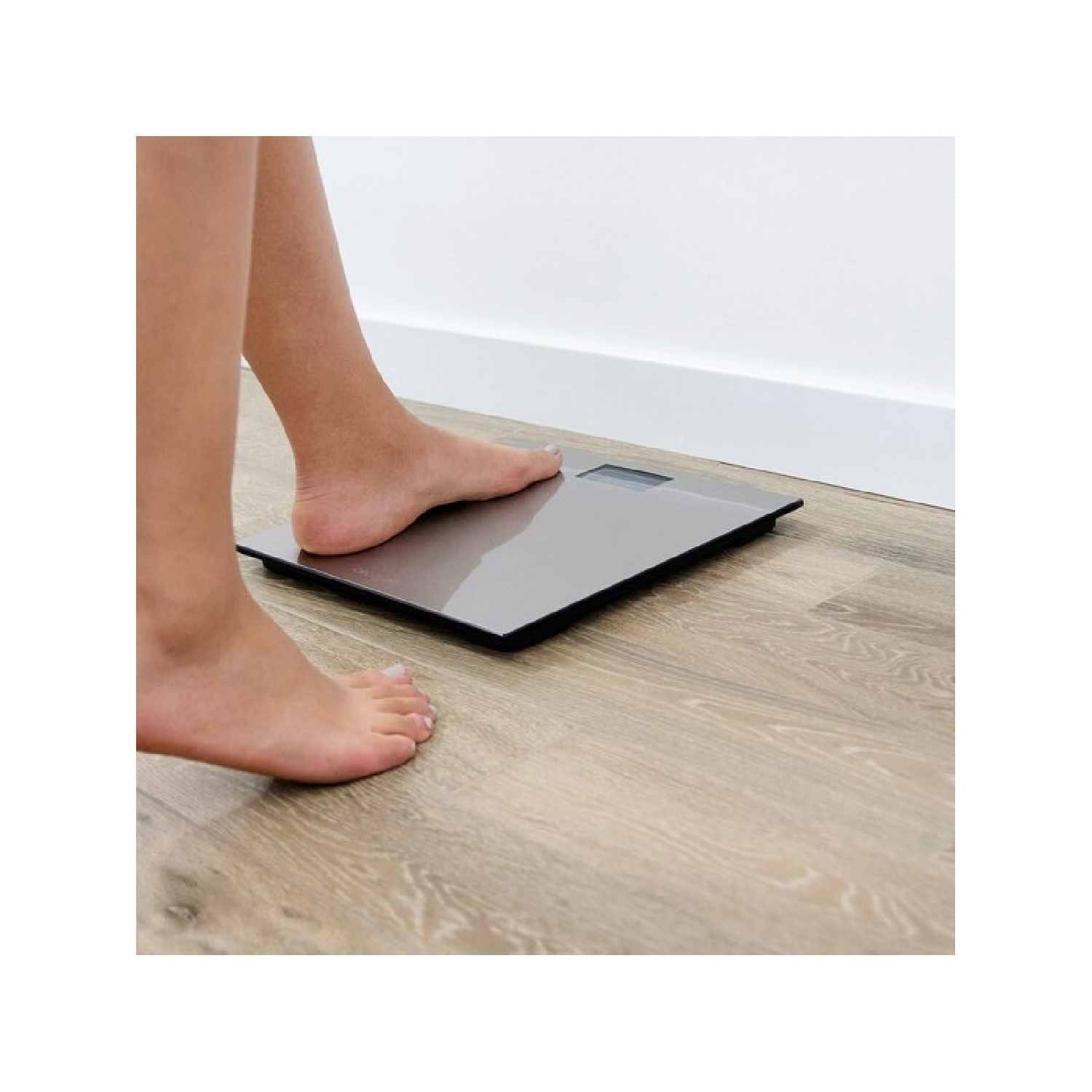 Eine Person tritt auf eine digitale Personenwaage auf einem Holzboden.