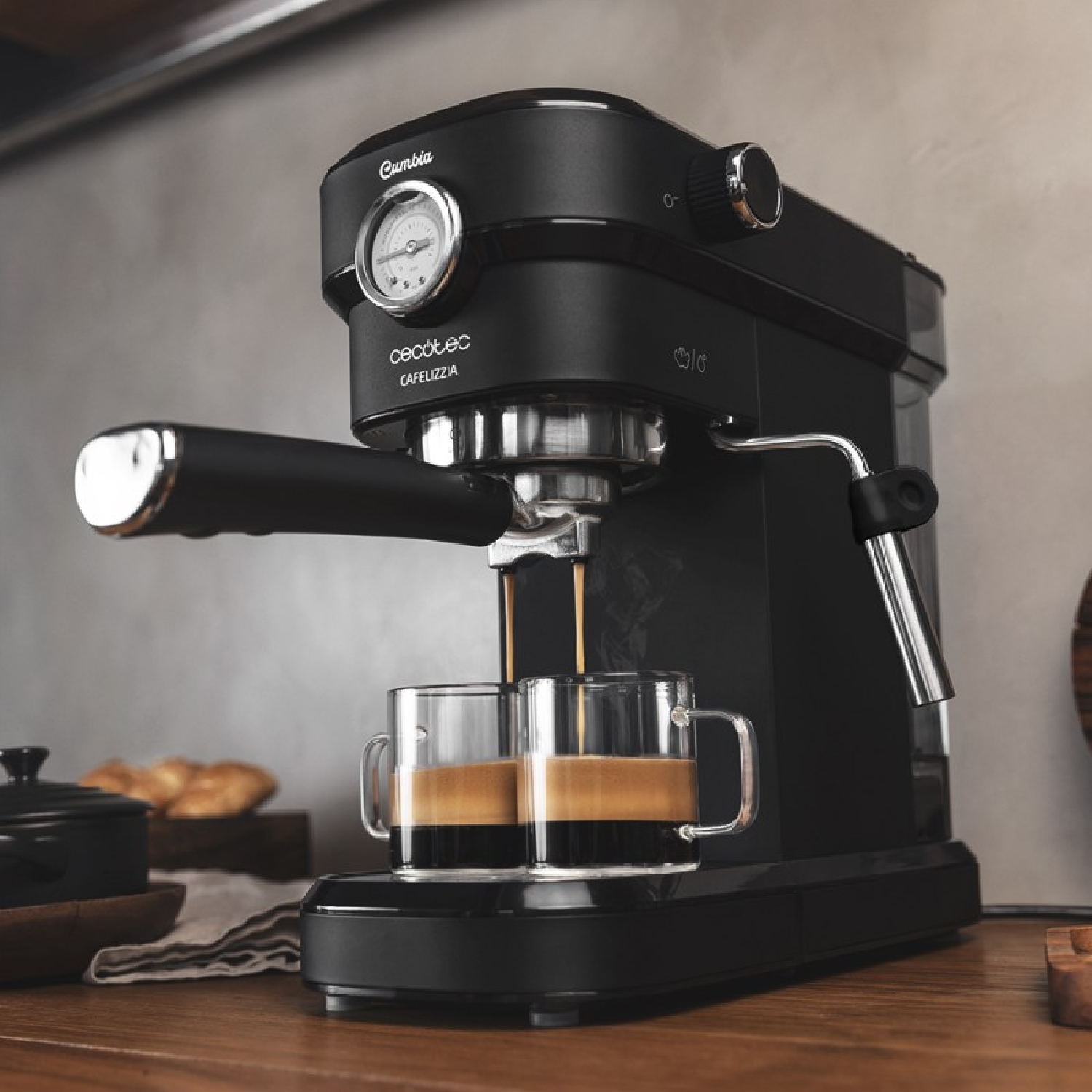 Eine schwarze Espressomaschine brüht zwei Tassen Espresso auf einem Holztisch.
