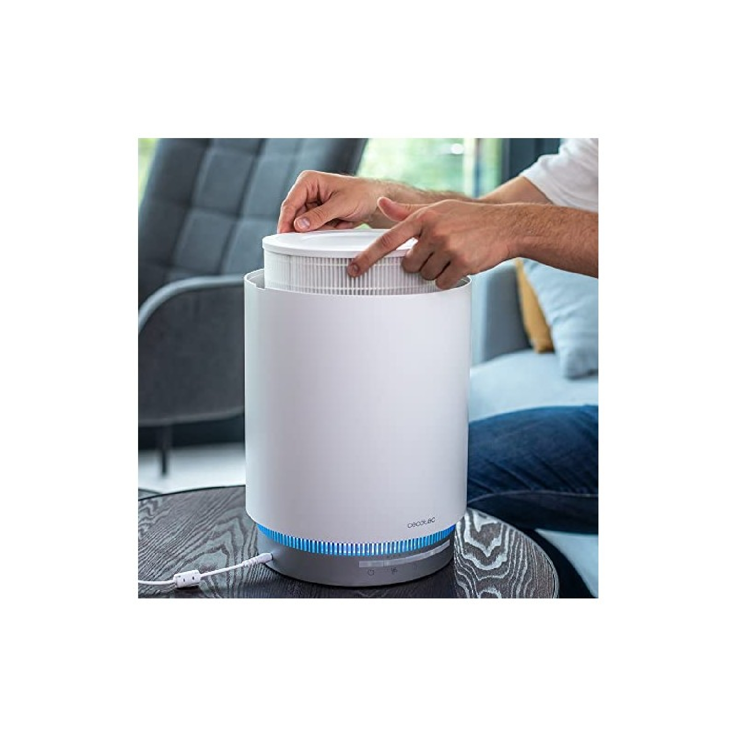 Una persona inserisce un filtro in un purificatore d'aria bianco. Luci blu brillano alla base.